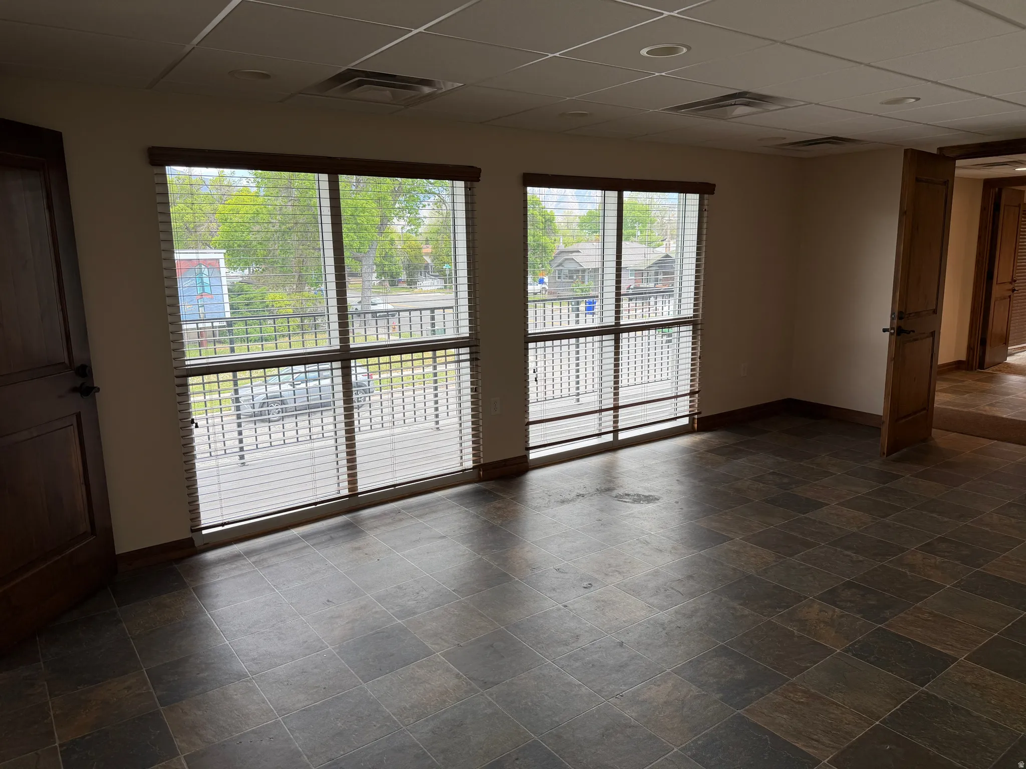 Empty room featuring a drop ceiling and dark stone finish floors