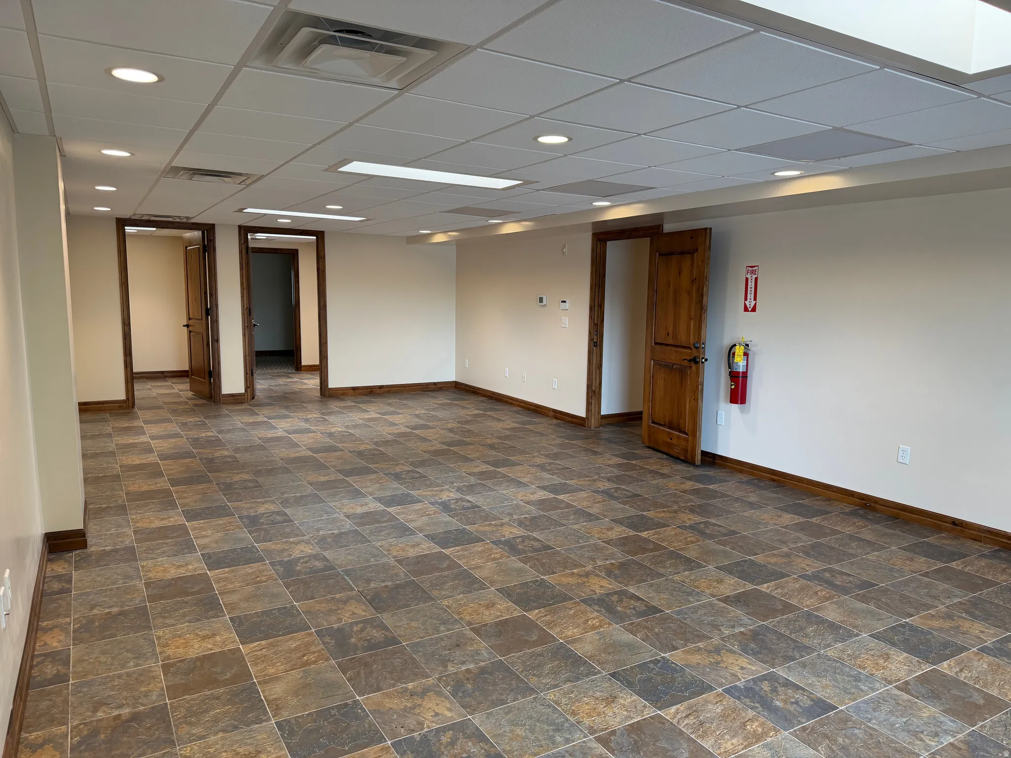 Unfurnished room featuring a drop ceiling, stone finish flooring, and recessed lighting