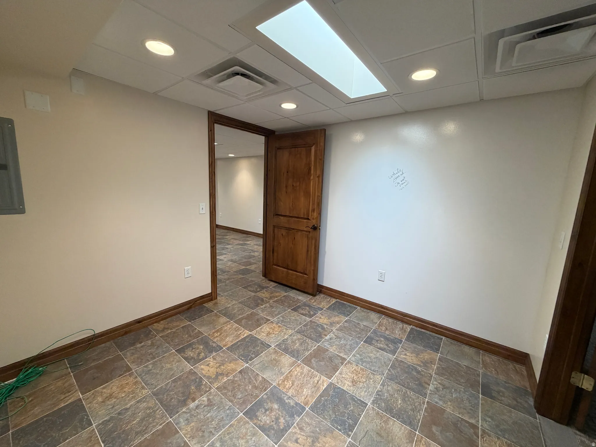 Empty room featuring recessed lighting, dark stone finish floors, electric panel, and a drop ceiling