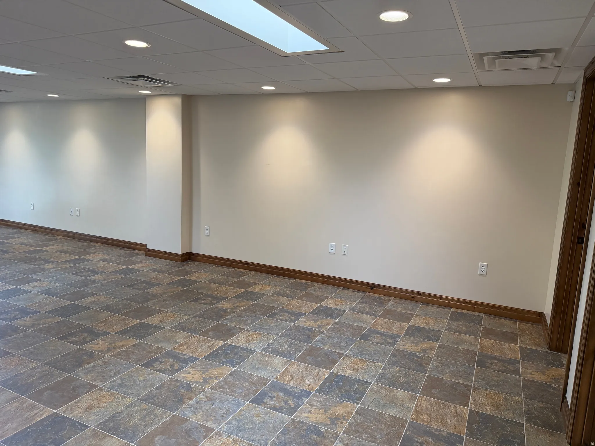 Unfurnished room with a drop ceiling, stone finish floors, and recessed lighting