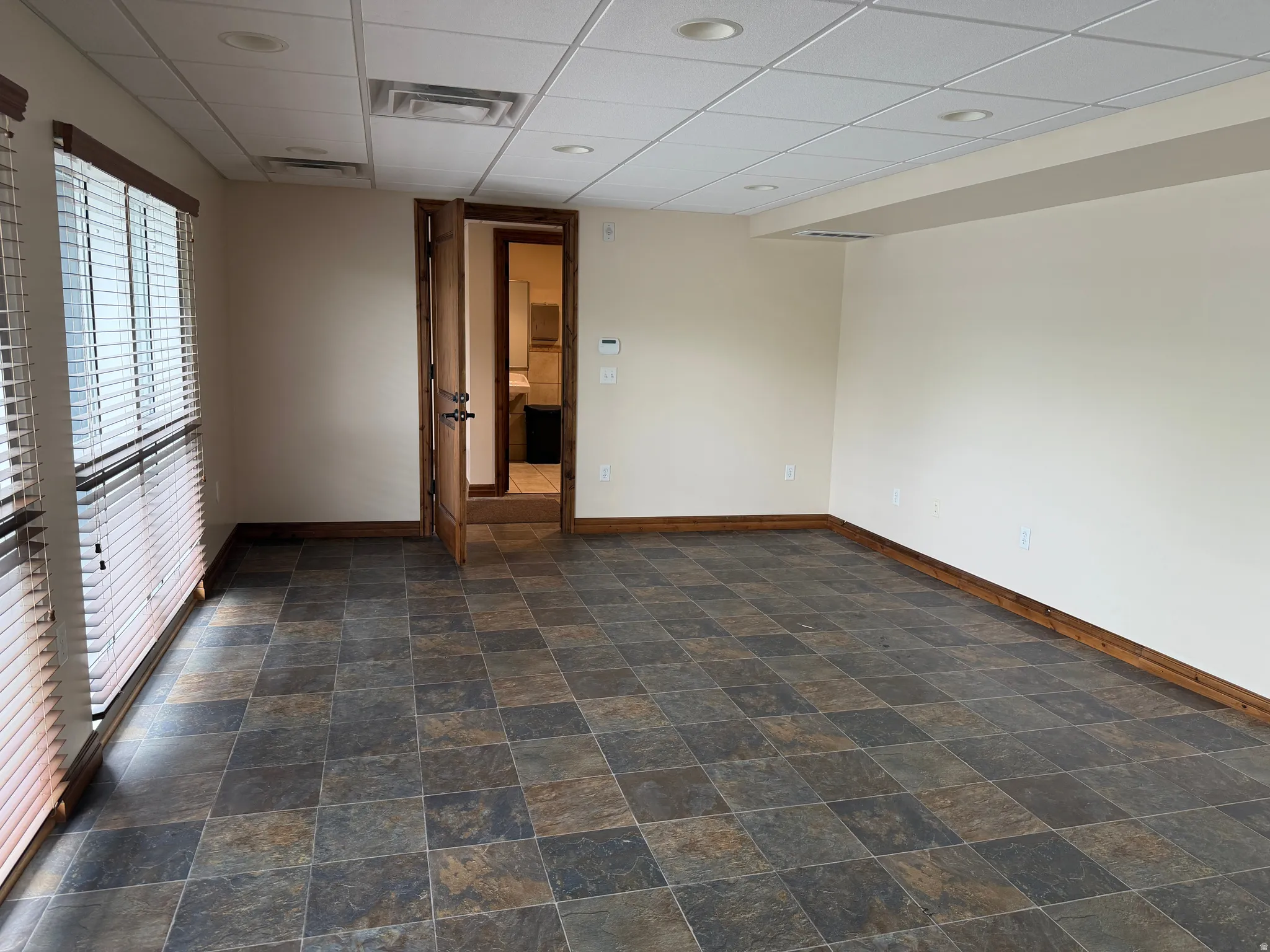Spare room featuring a drop ceiling and stone finish flooring