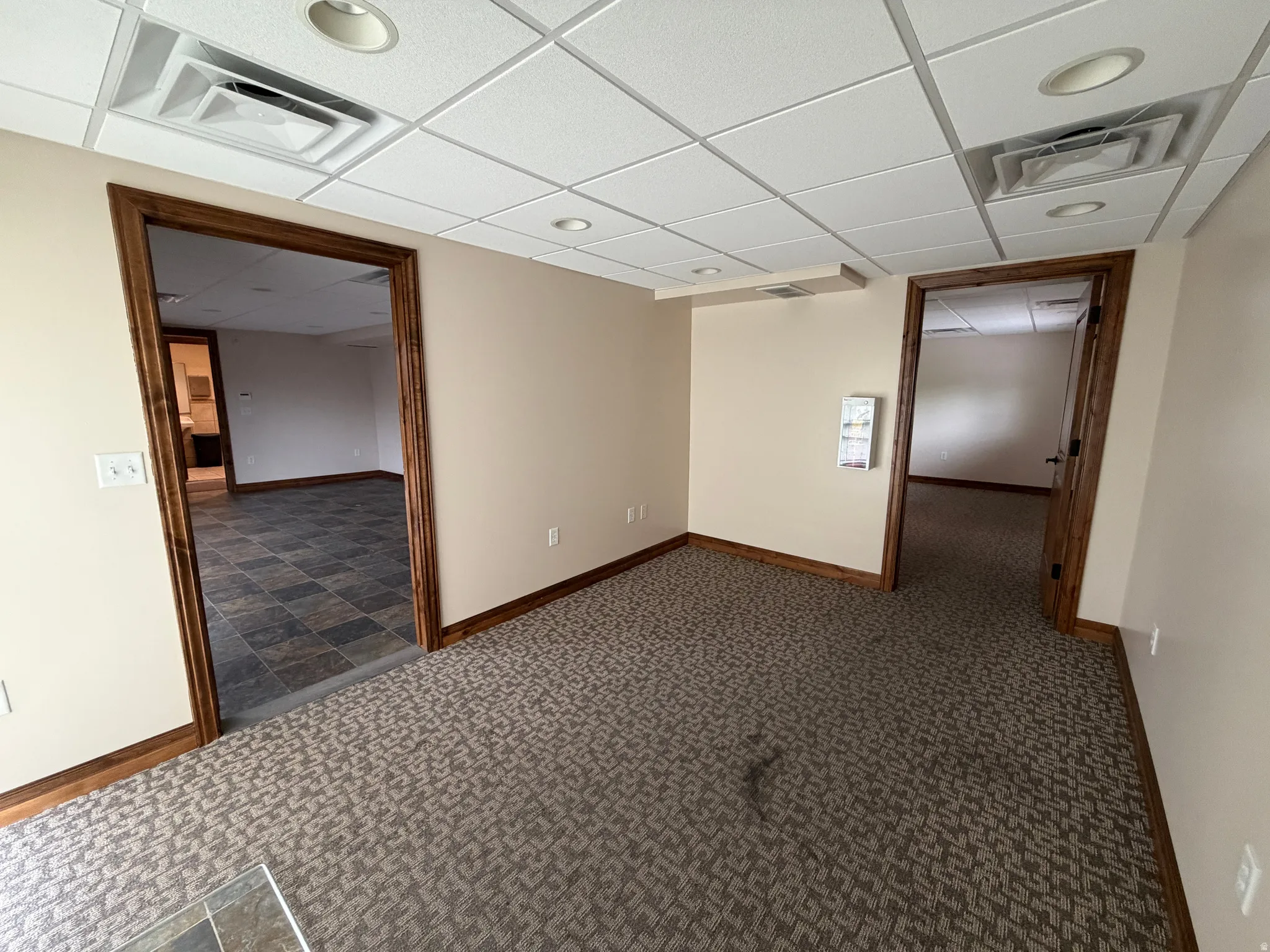 Empty room featuring dark colored carpet and a paneled ceiling