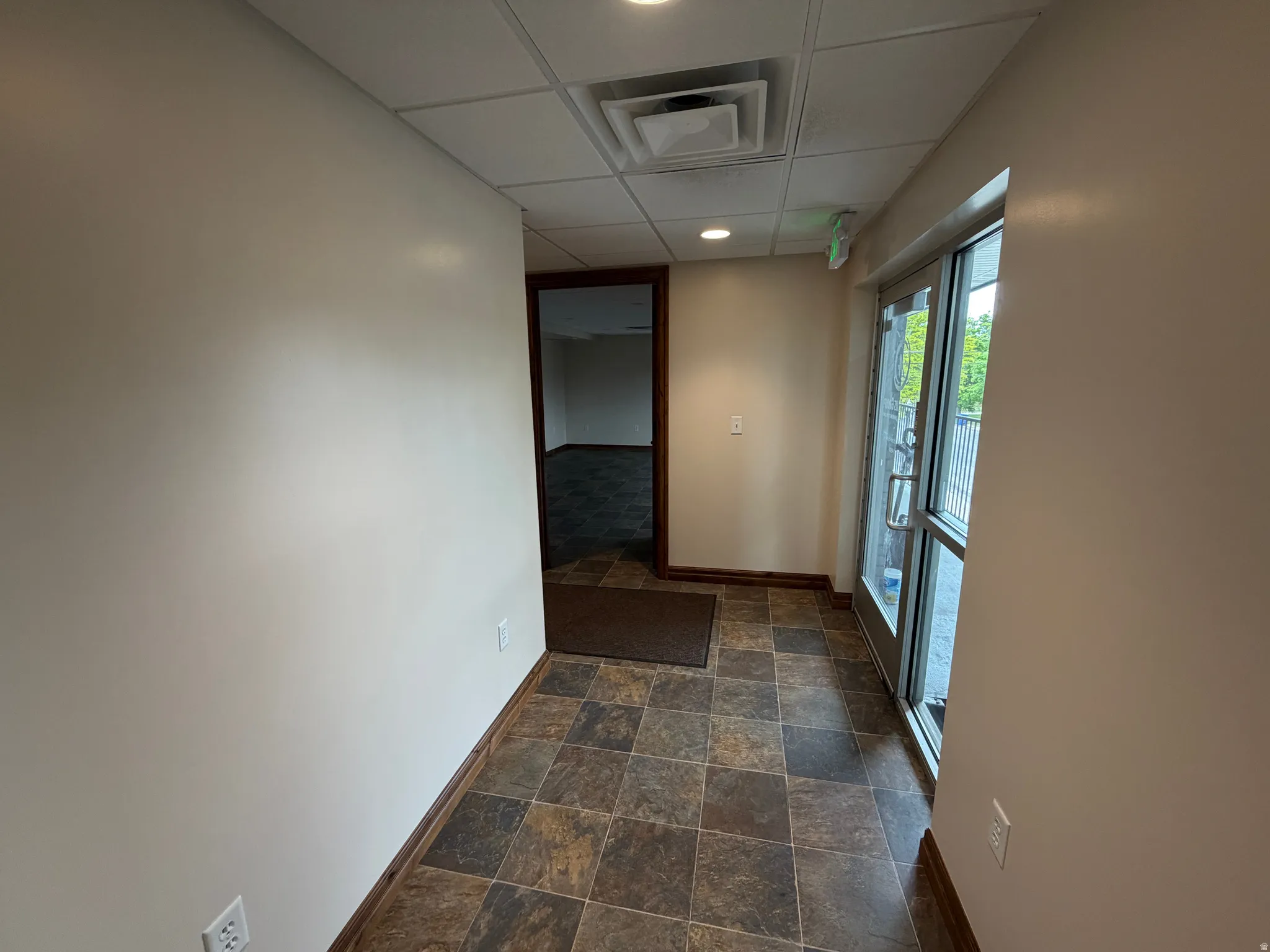 Hall featuring dark stone finish floors, recessed lighting, and a paneled ceiling