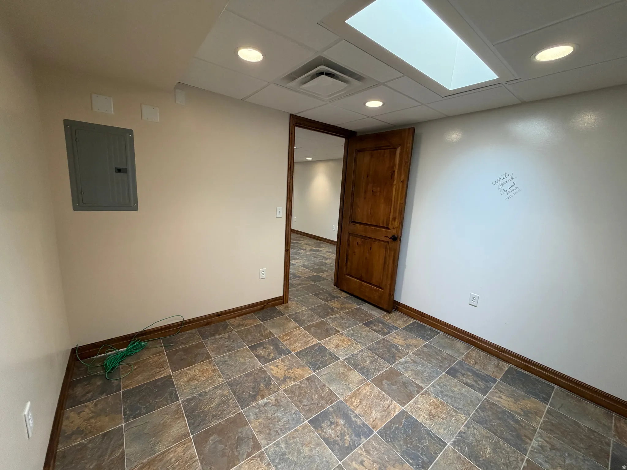 Spare room with electric panel, recessed lighting, and dark stone finish flooring