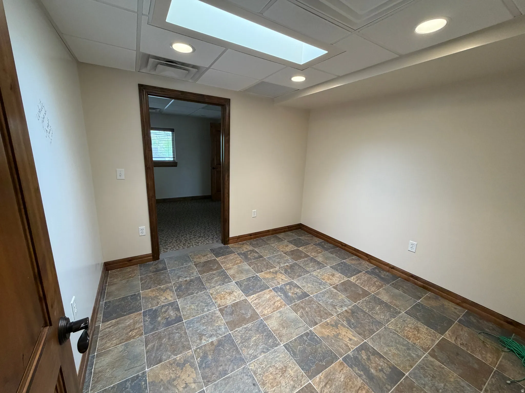 Unfurnished room featuring dark stone finish floors, recessed lighting, and a paneled ceiling