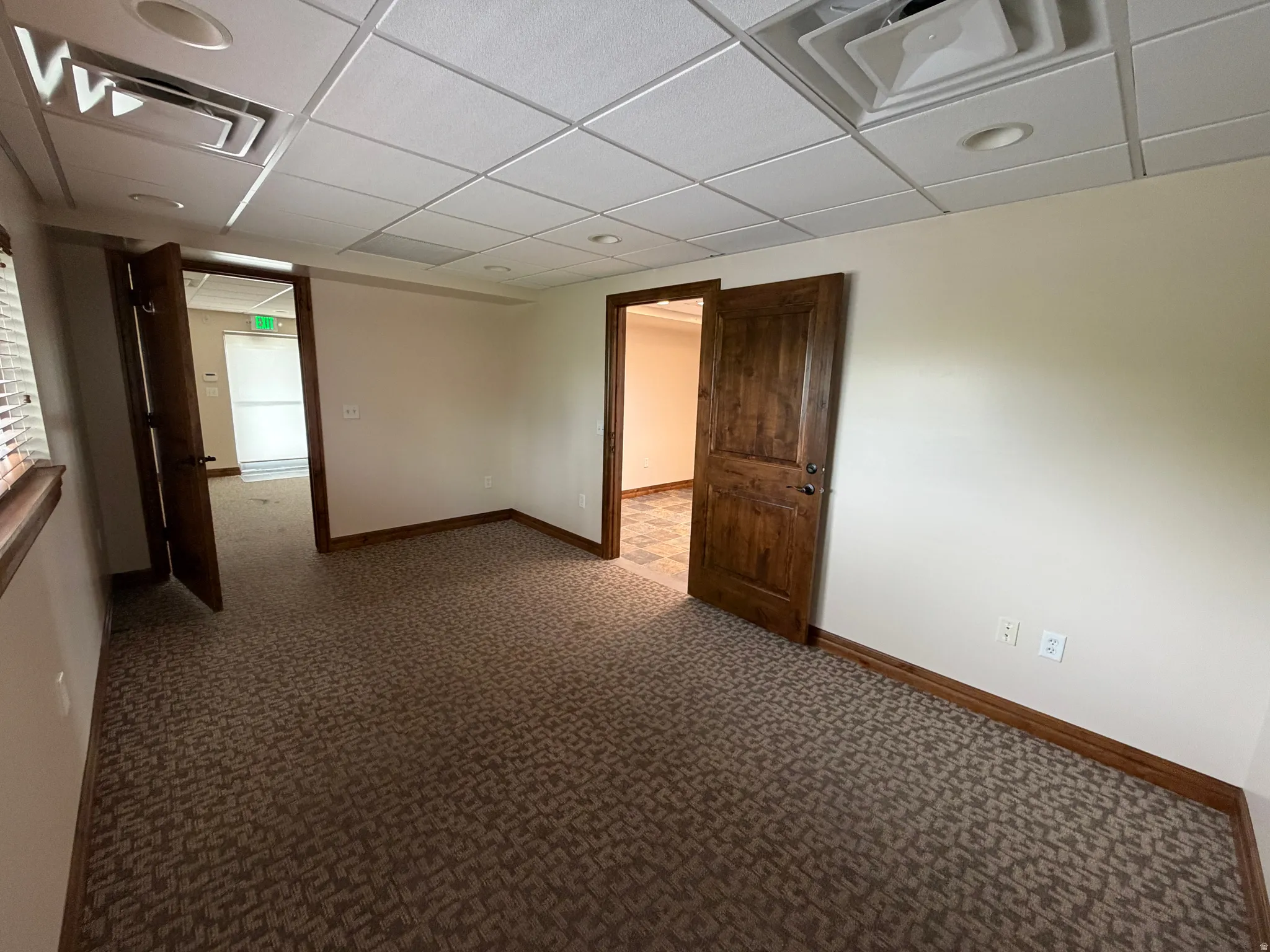 Carpeted empty room with baseboards and a paneled ceiling