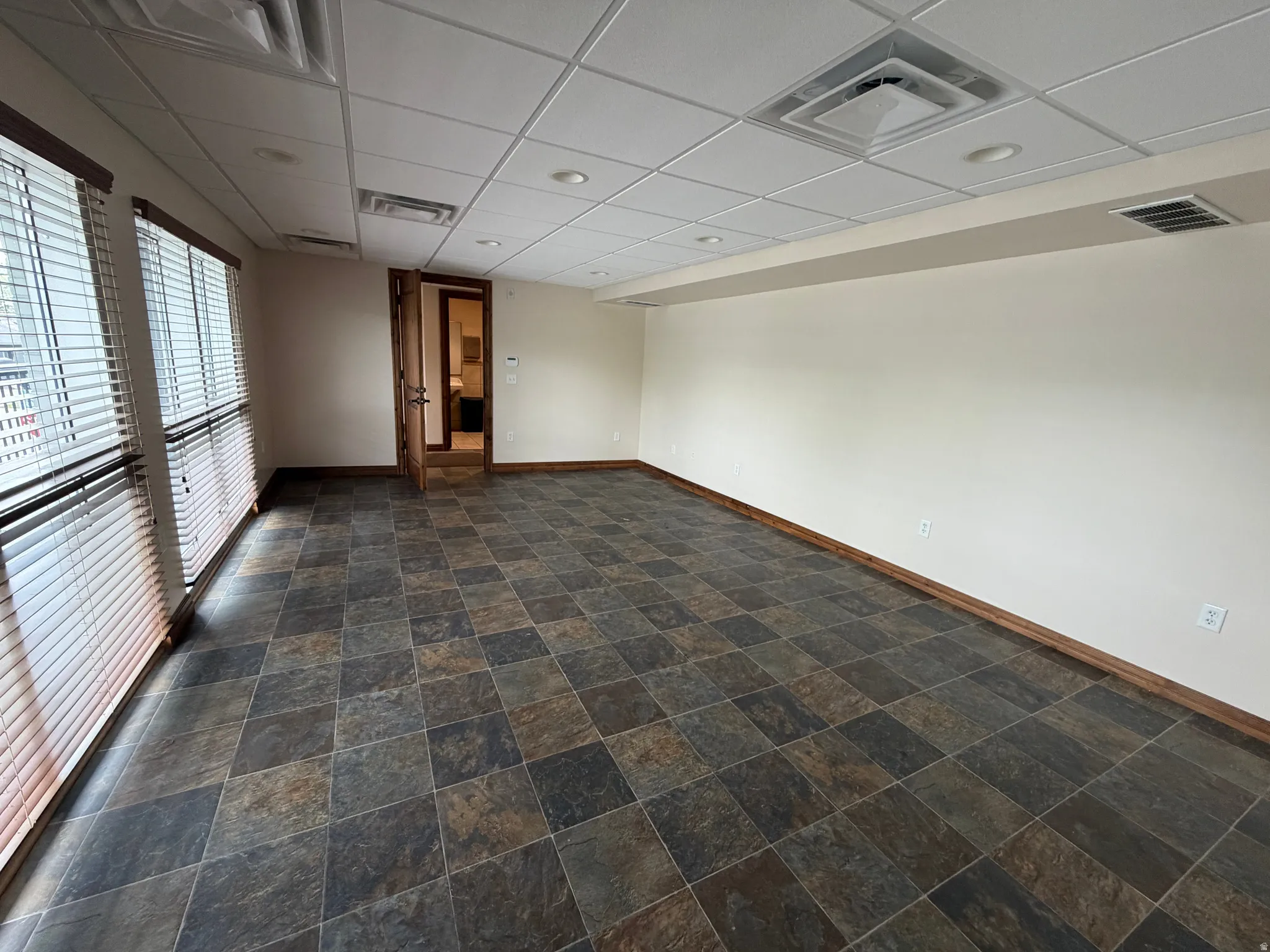 Spare room featuring a drop ceiling and dark stone finish flooring