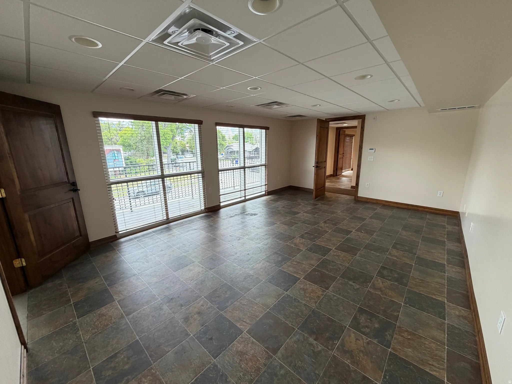 Empty room with a drop ceiling and dark stone finish flooring