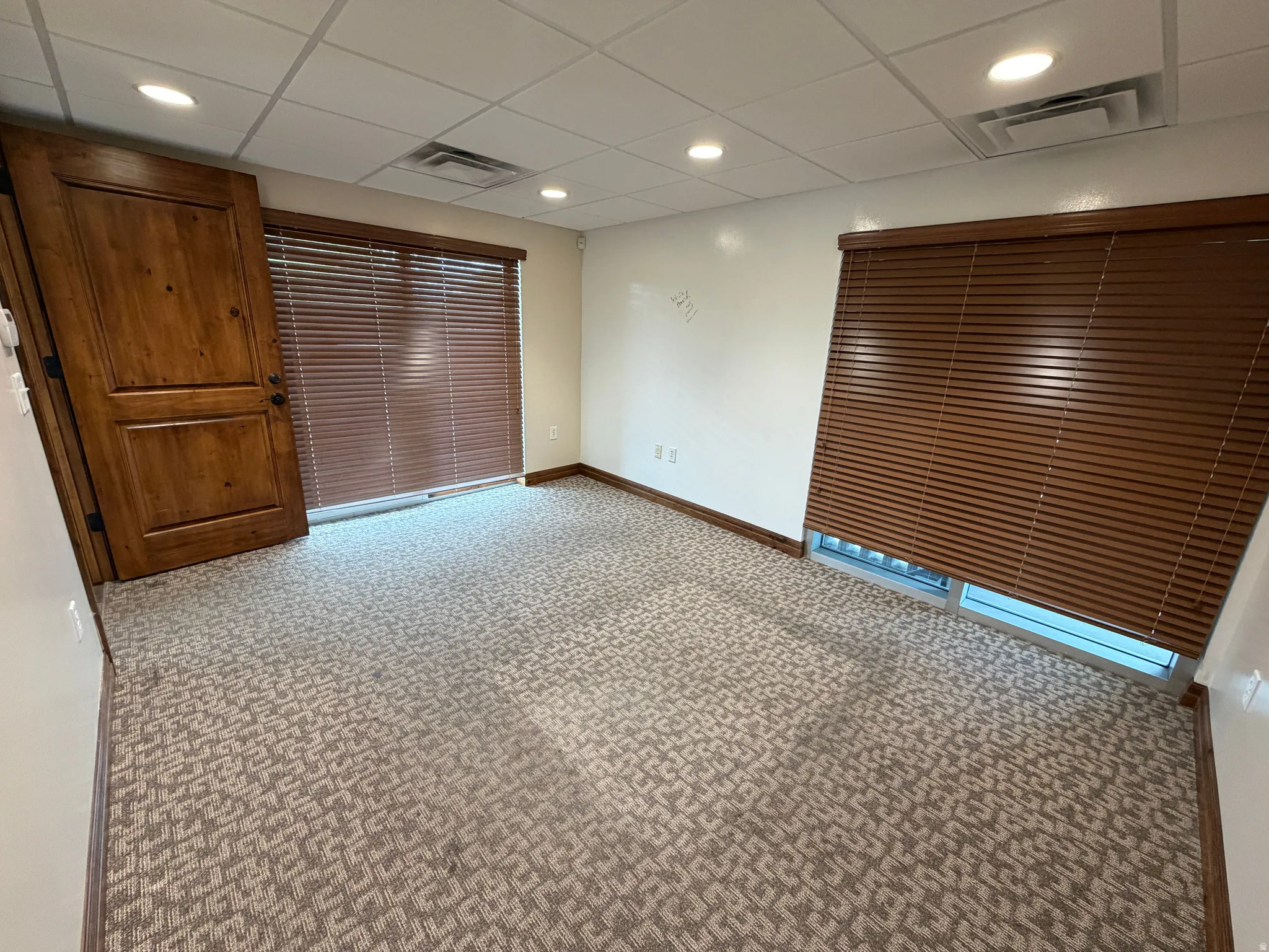 Empty room featuring light carpet, a drop ceiling, and recessed lighting