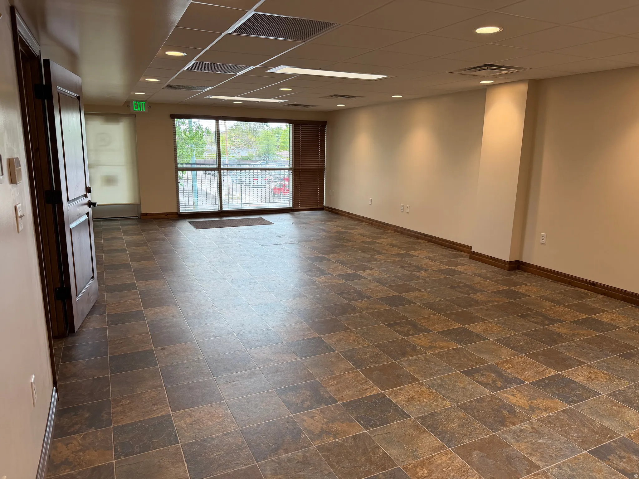 Empty room featuring a drop ceiling, recessed lighting, and stone finish floors