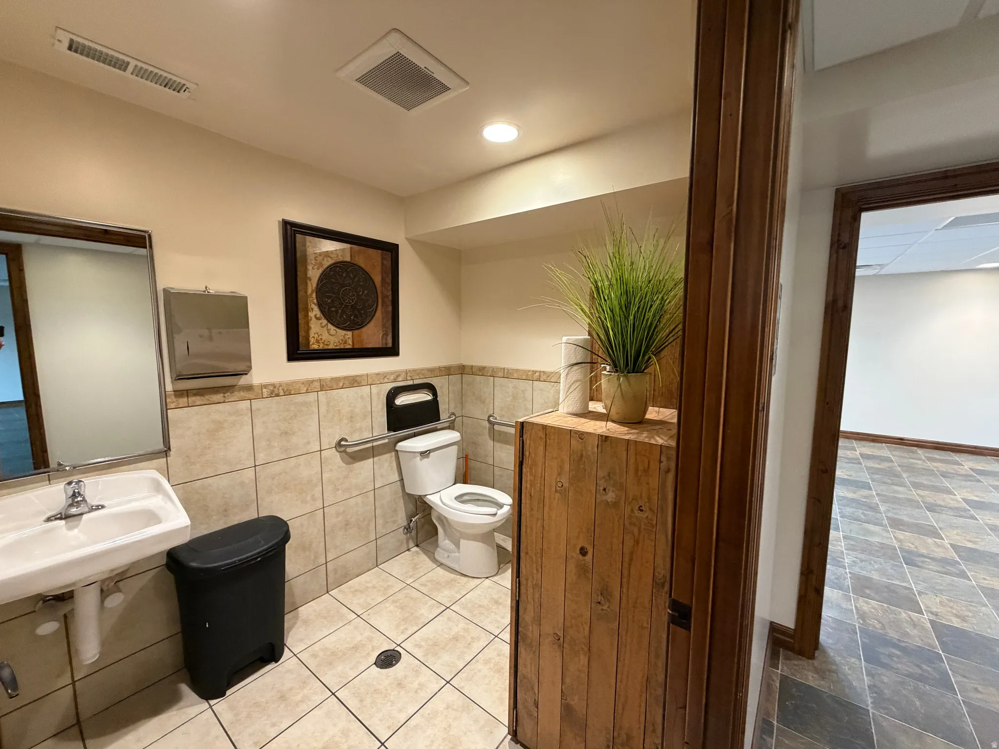 Half bathroom with tile walls and a wainscoted wall