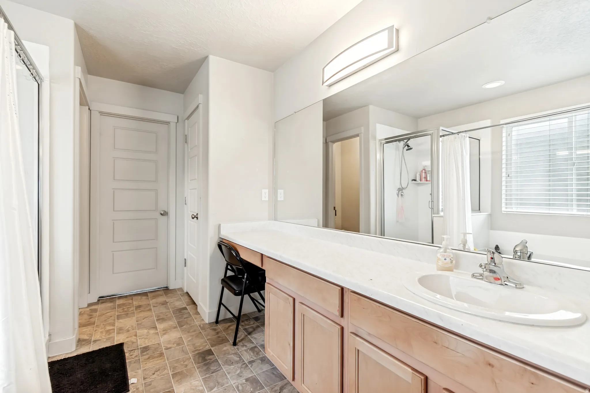 Bathroom featuring vanity, stone finish floors, a stall shower, and a closet