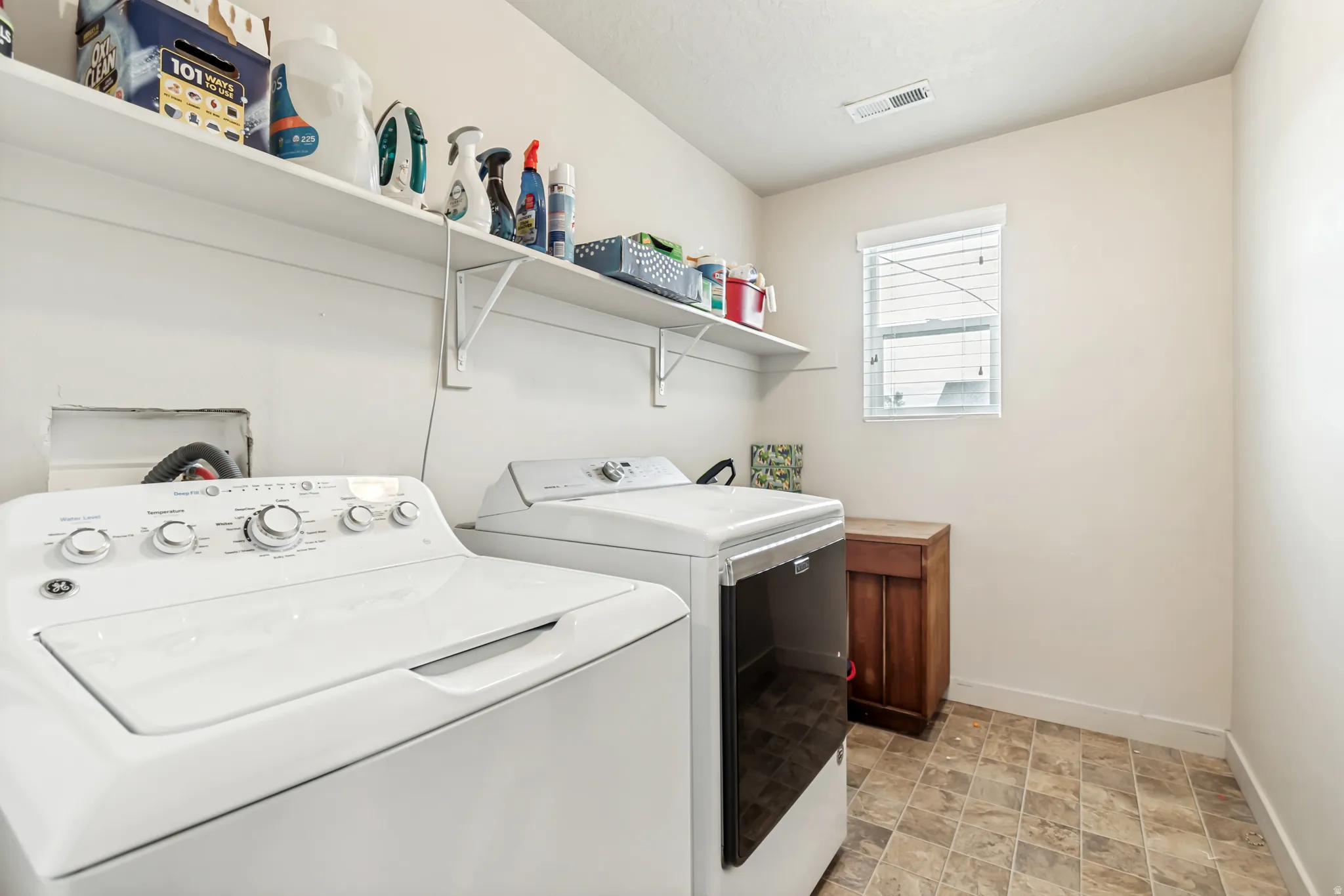 Laundry area with washing machine and clothes dryer and stone finish flooring