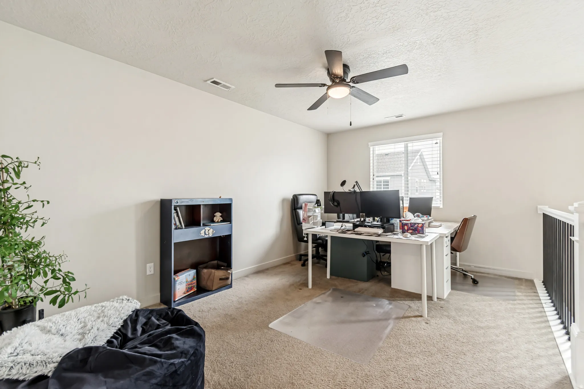 Carpeted home office with a textured ceiling and ceiling fan
