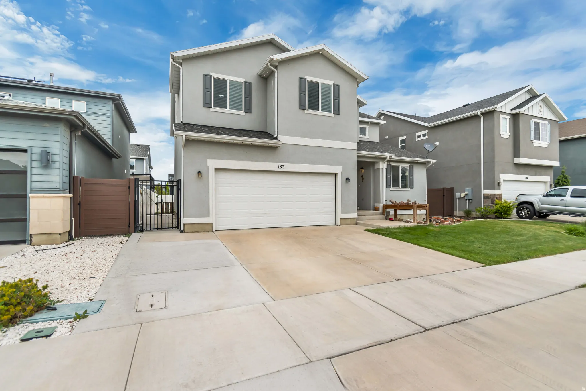 Traditional-style home featuring a gate, a garage, concrete driveway, and stucco siding