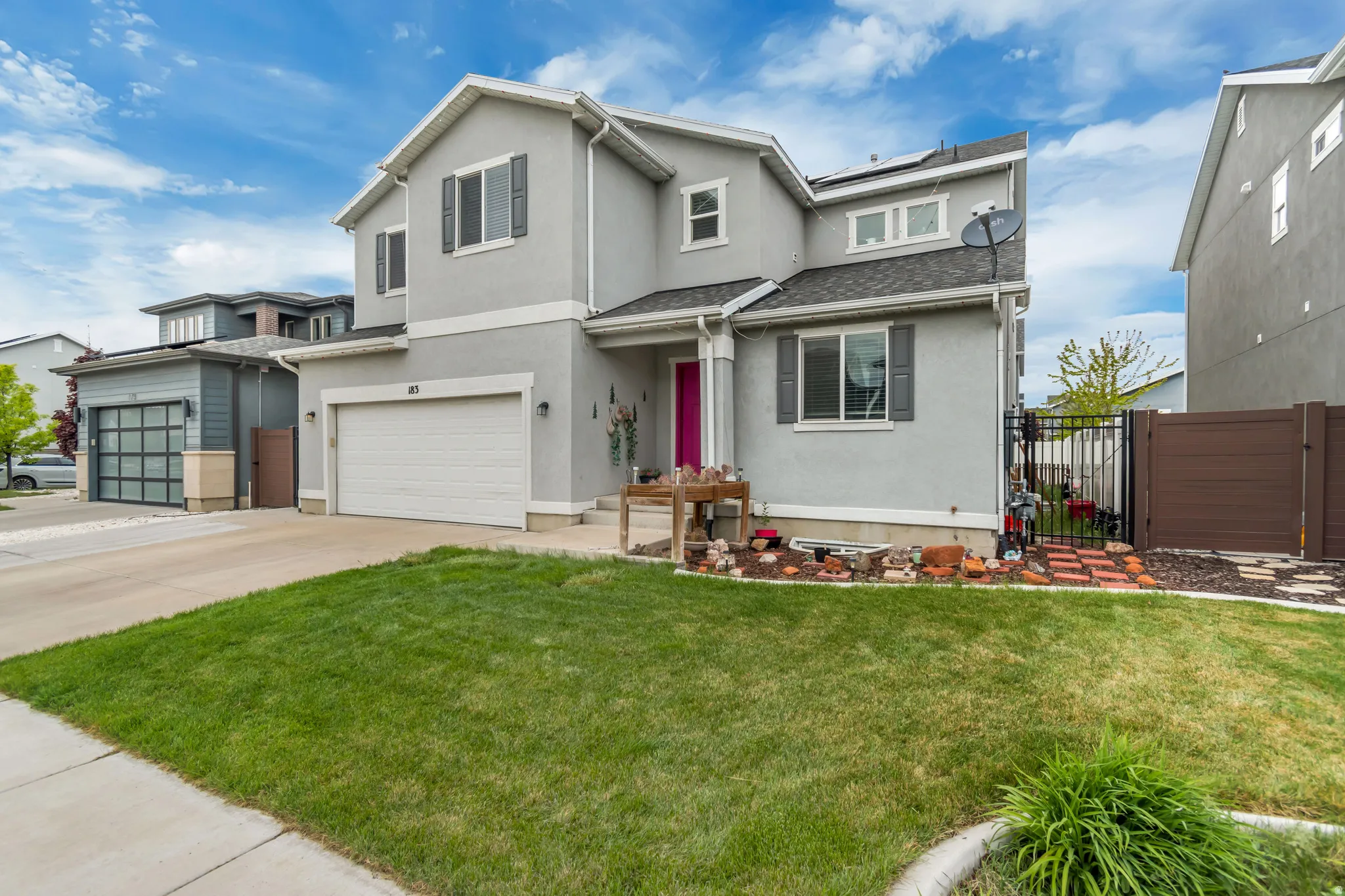 Traditional-style house featuring a gate, roof mounted solar panels, stucco siding, and an attached garage