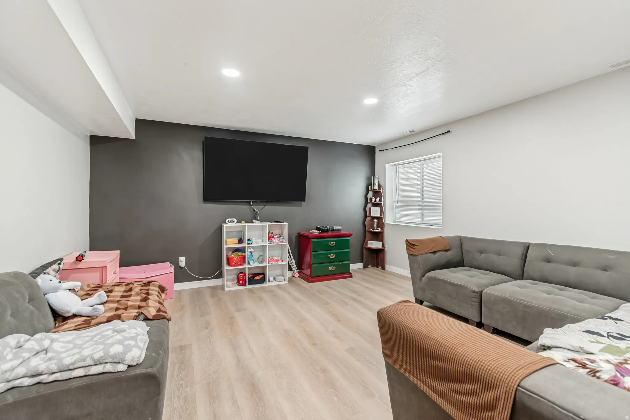 Living area with light wood finished floors and recessed lighting