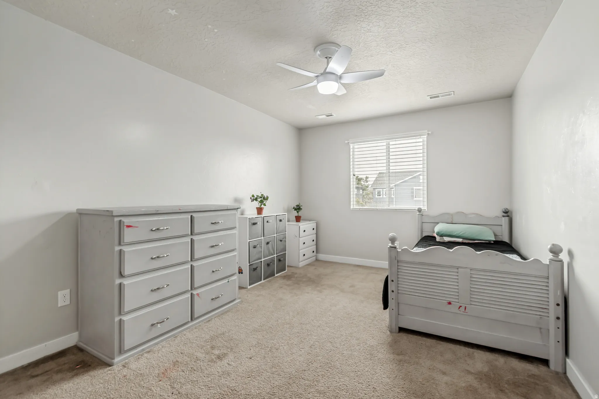 Bedroom featuring ceiling fan, light colored carpet, and a textured ceiling