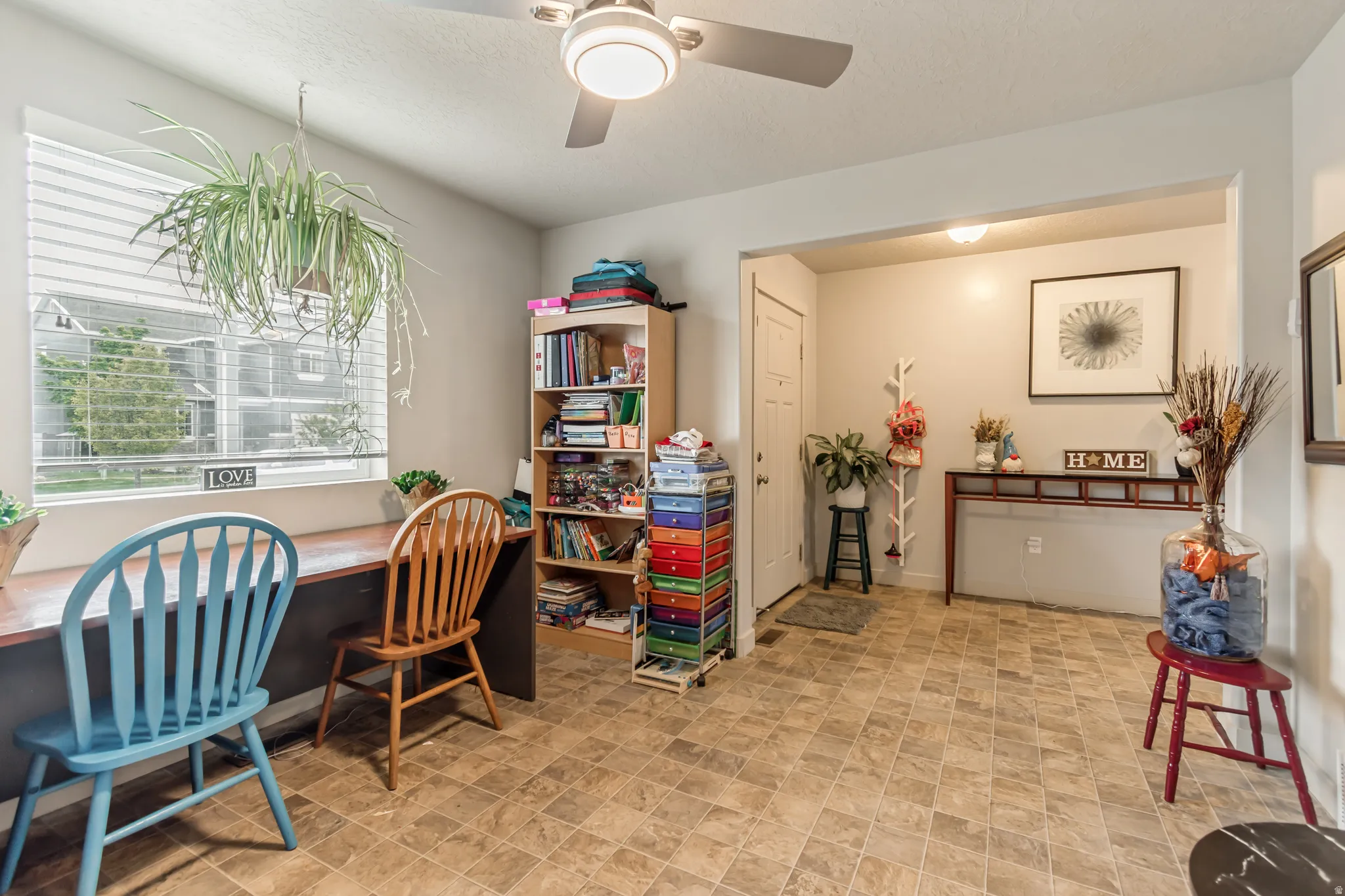 Home office featuring a ceiling fan, built in study area, and stone finish flooring