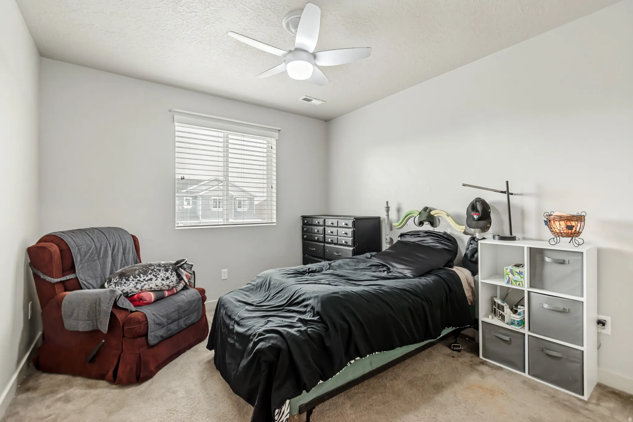 Carpeted bedroom featuring ceiling fan and a textured ceiling