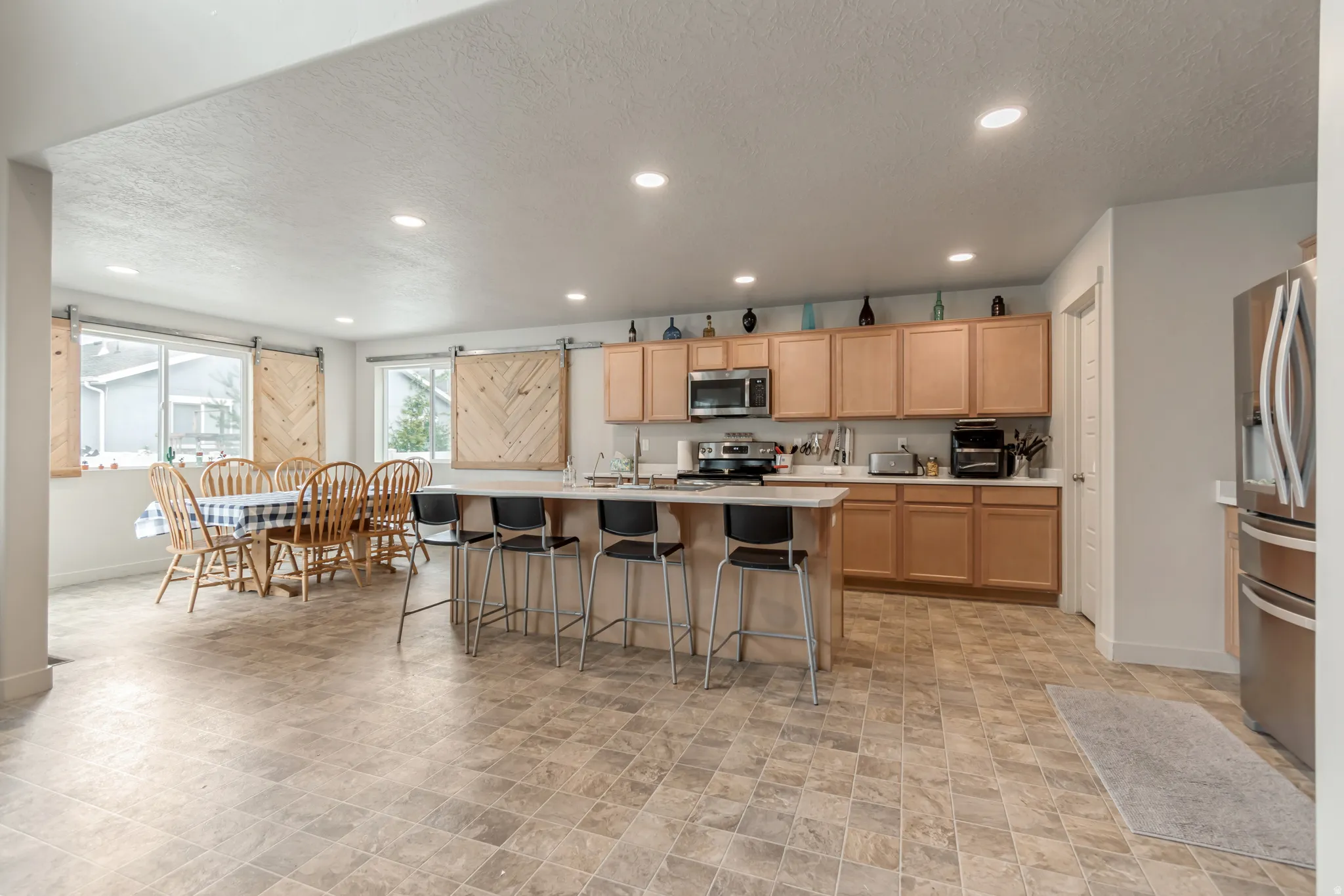 Kitchen featuring a barn door, light countertops, a textured ceiling, a kitchen breakfast bar, and stainless steel appliances