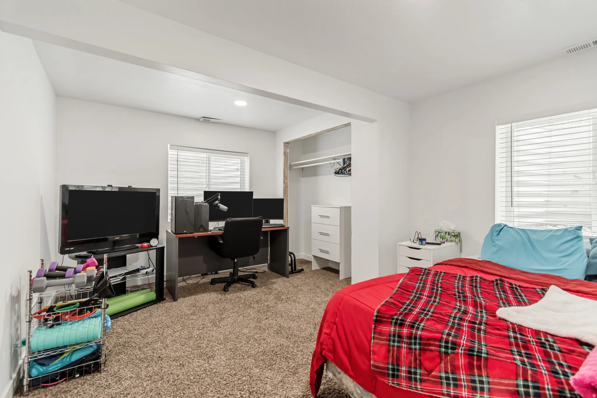 Bedroom featuring light carpet, an office area, and a closet