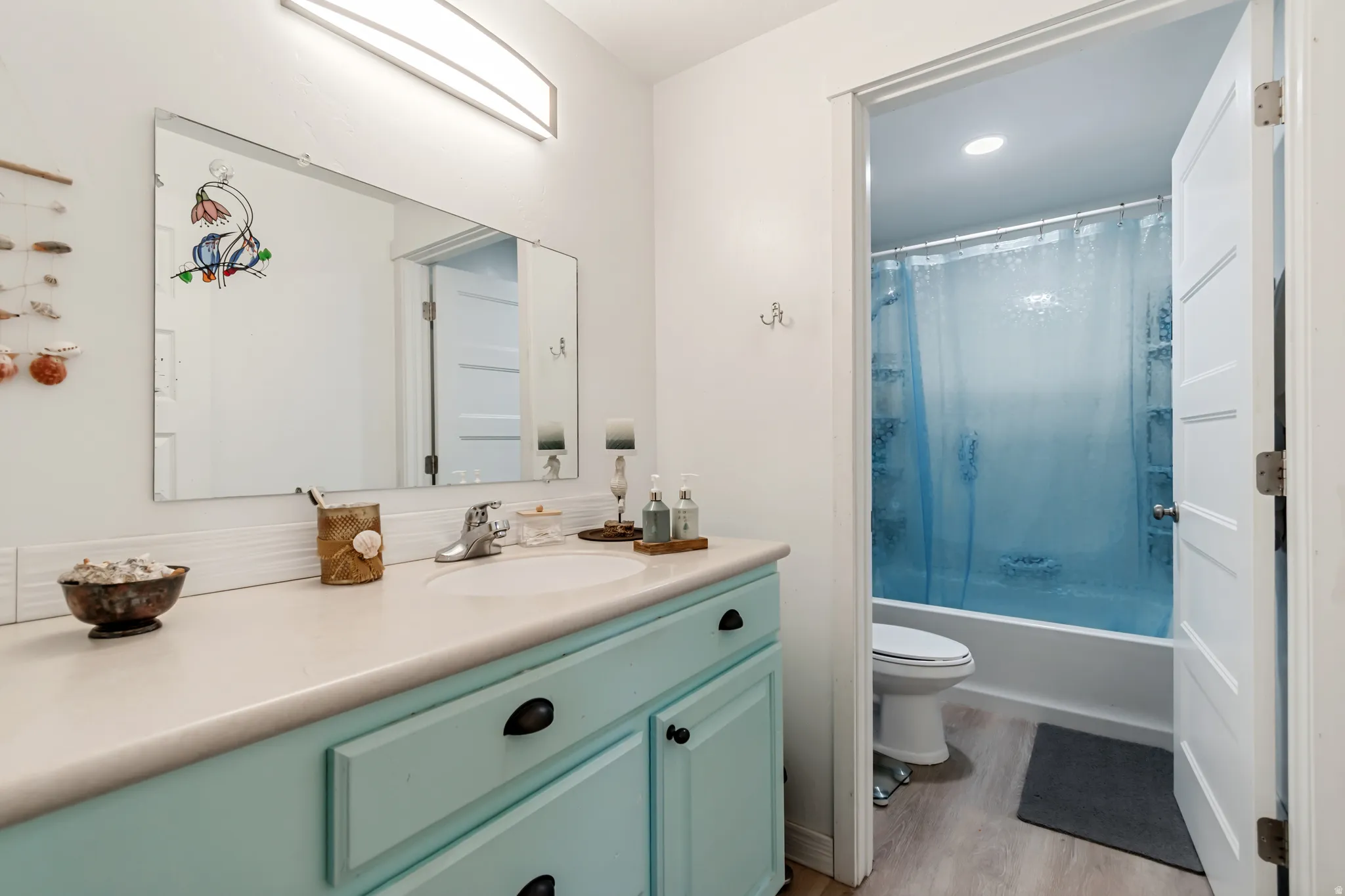Full bath with vanity, light wood-style flooring, and bath / shower combo with glass door