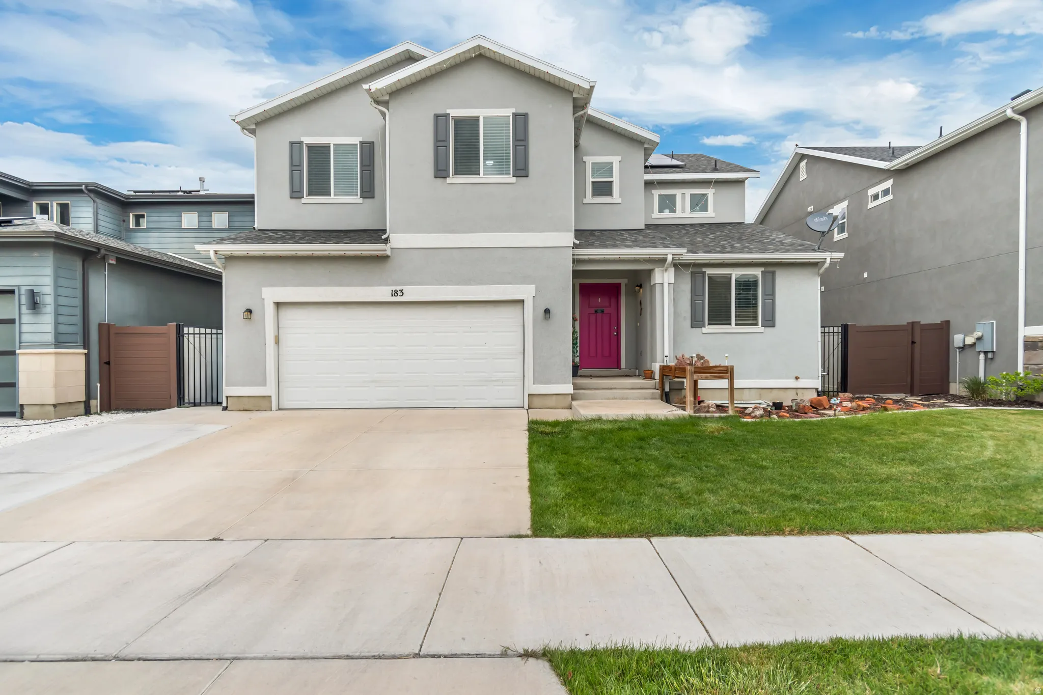 Traditional-style house featuring a gate, stucco siding, an attached garage, driveway, and roof with shingles
