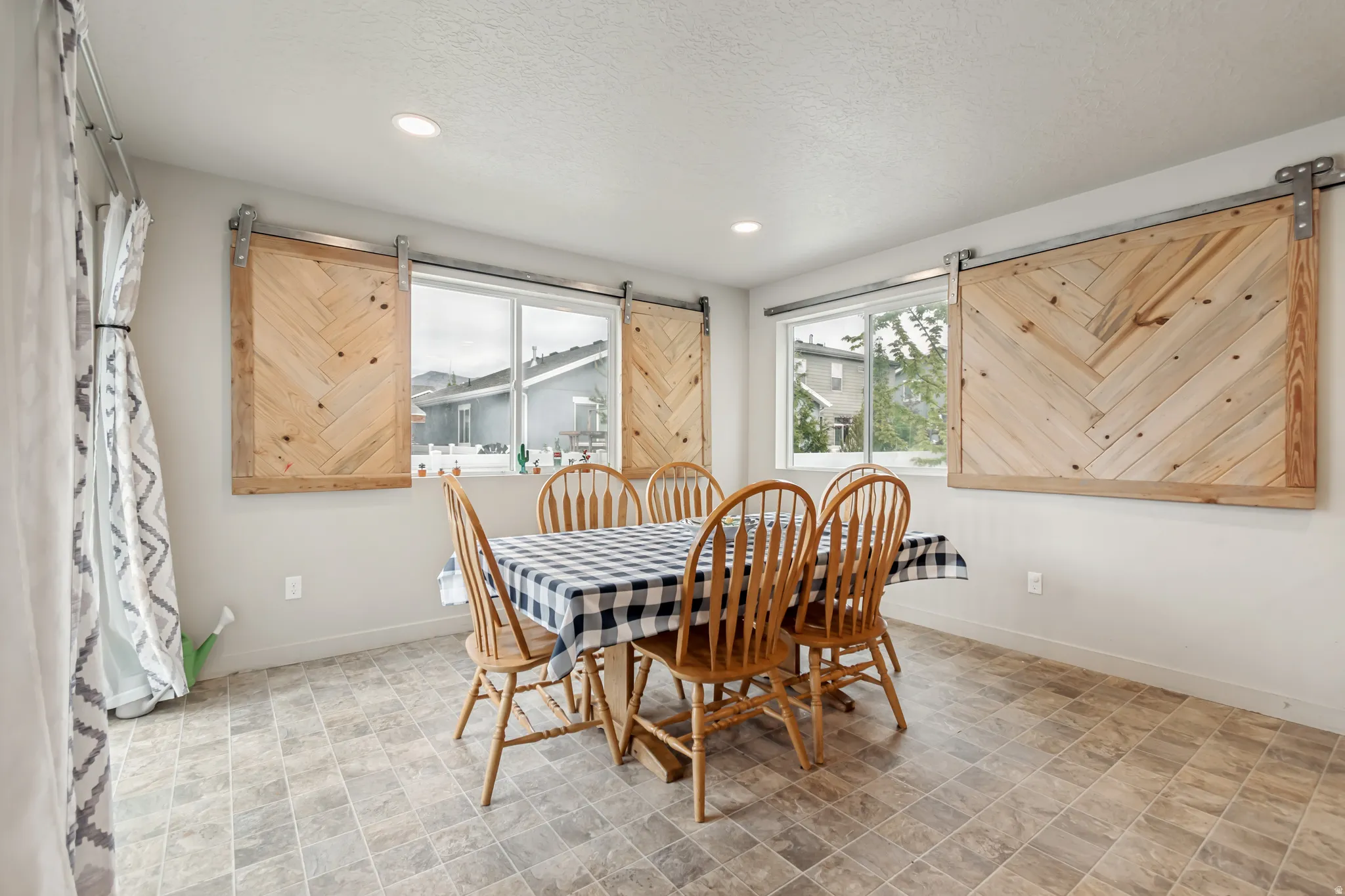 Dining area with a barn door, stone finish flooring, and recessed lighting