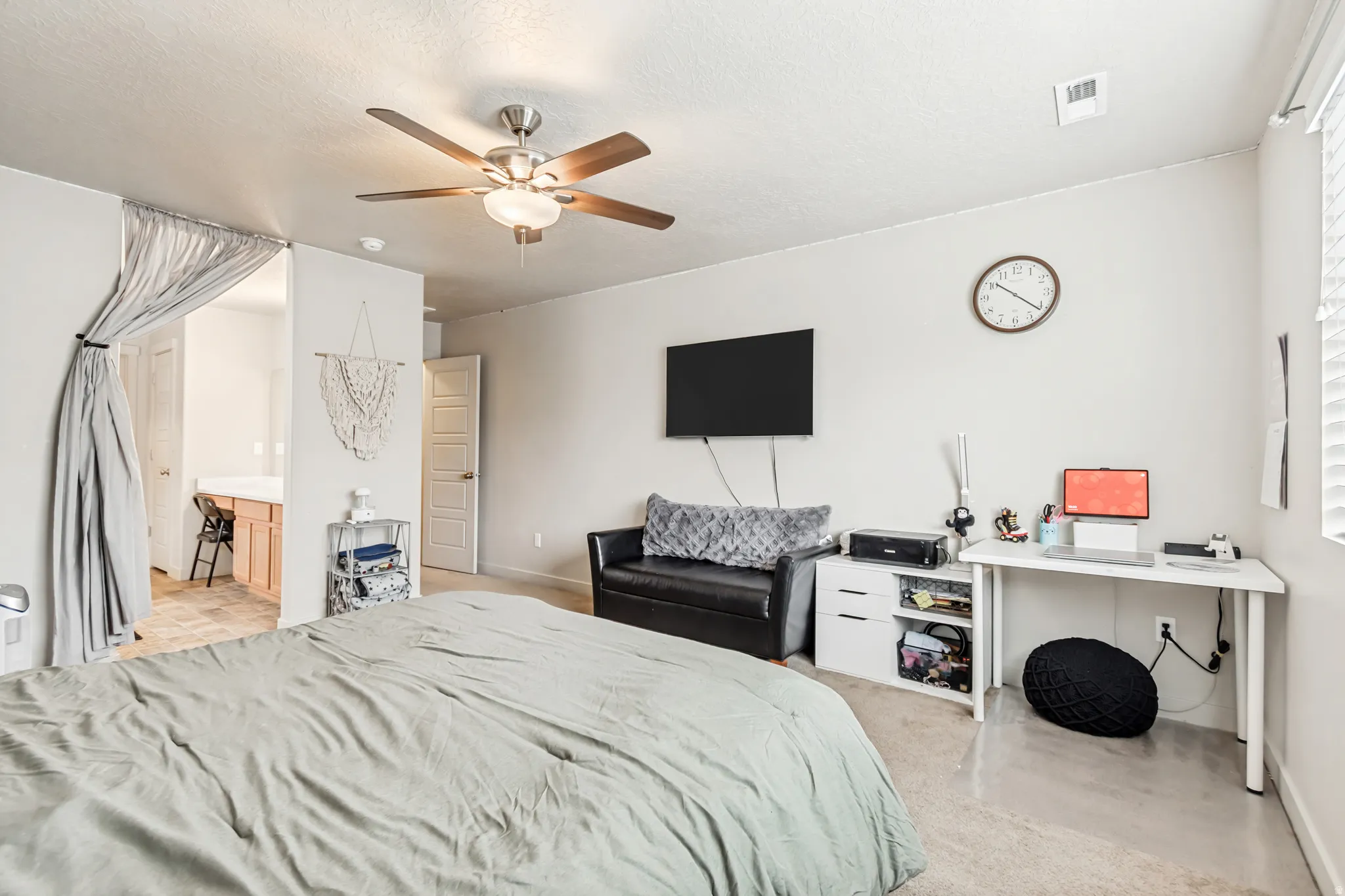 Bedroom with a ceiling fan, a textured ceiling, and light carpet