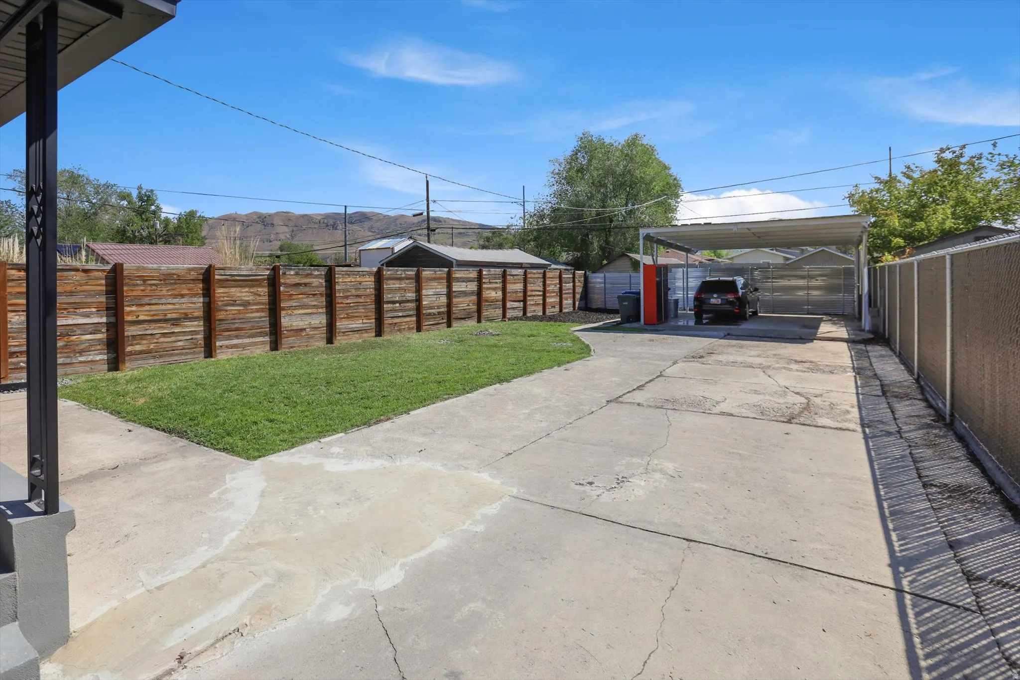 Fenced backyard with a carport, an outbuilding, and driveway