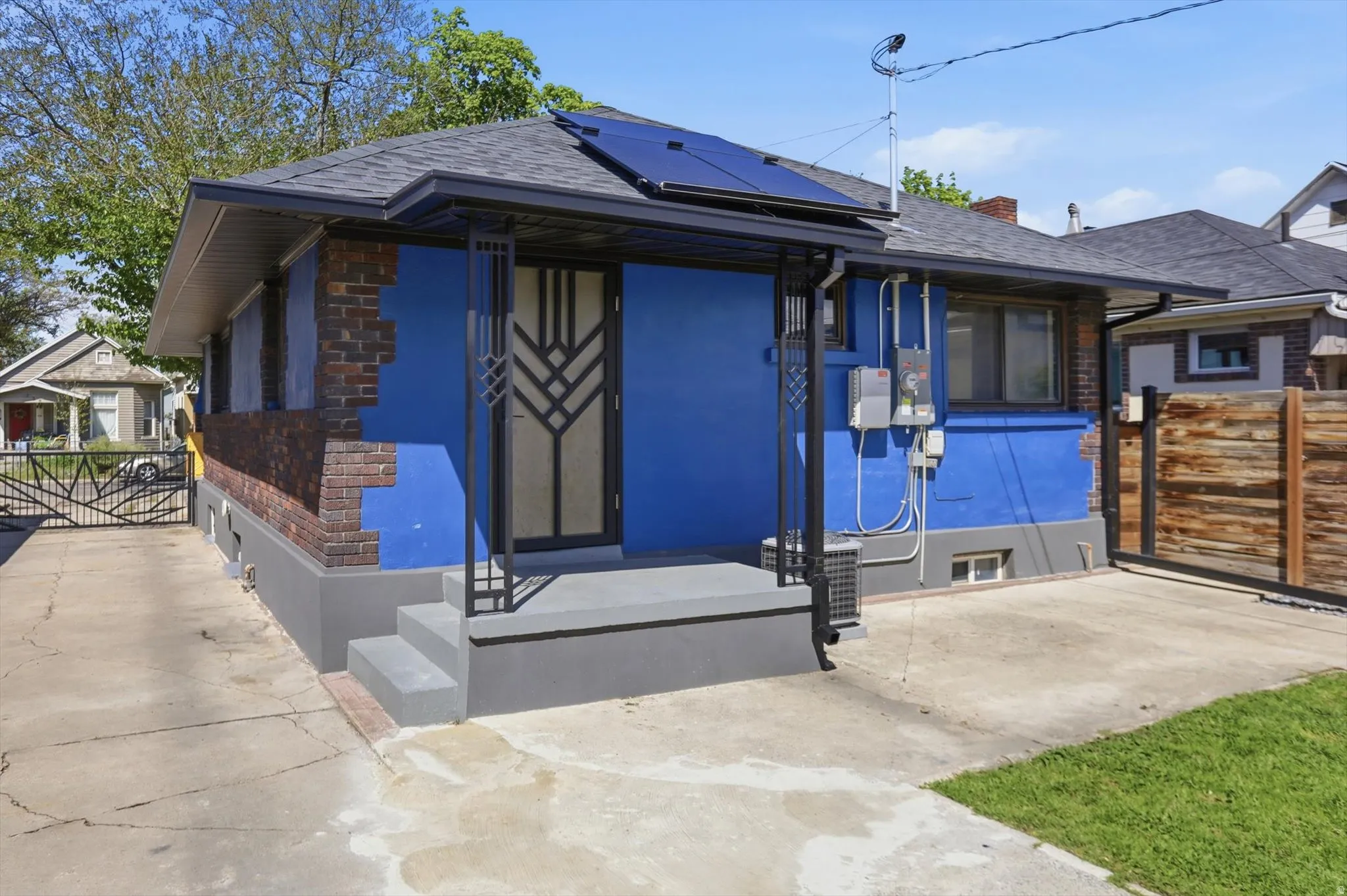 View of front facade with solar panels, a gate, and a shingled roof