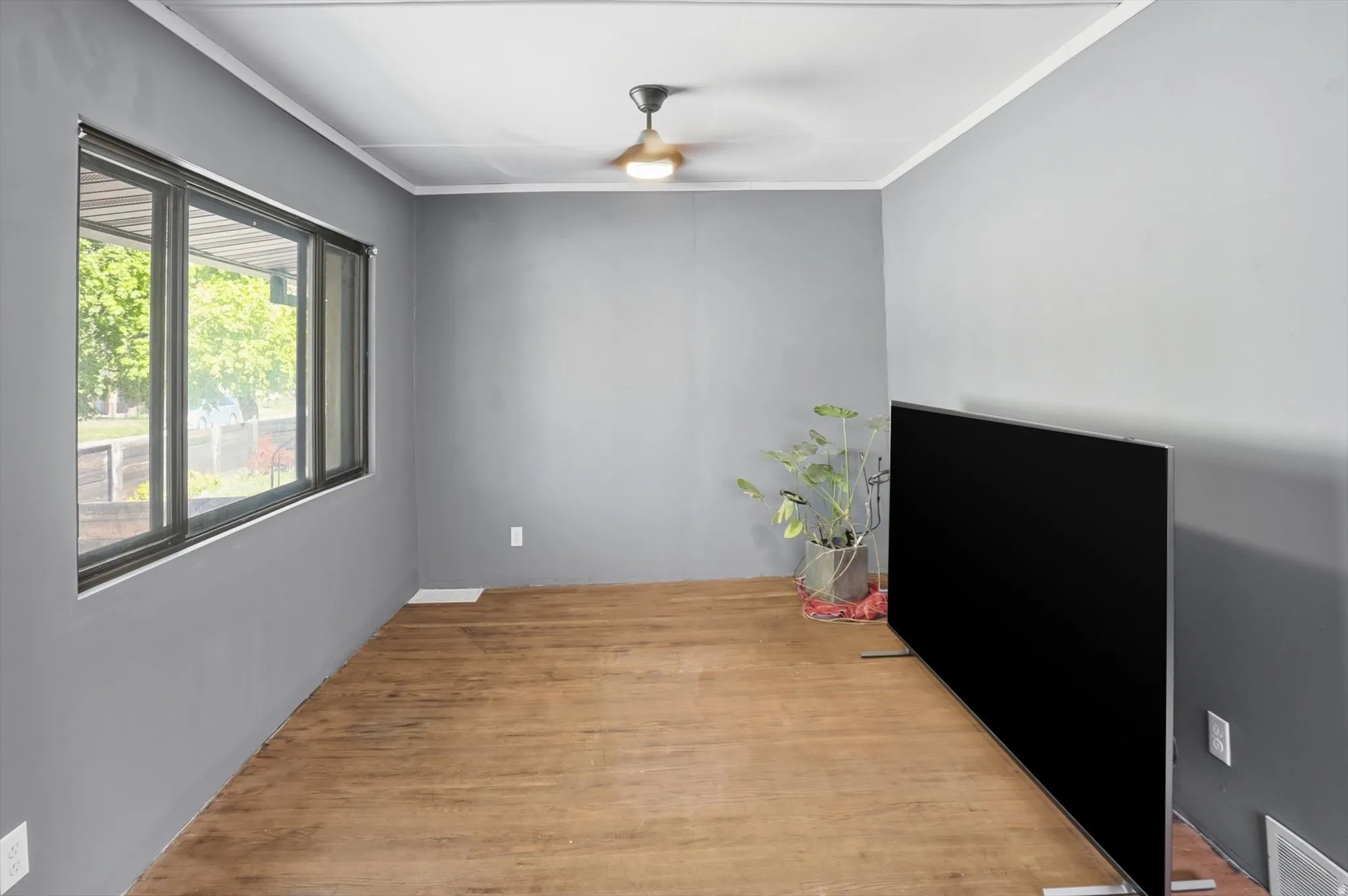Spare room featuring light wood finished floors, ornamental molding, and a ceiling fan