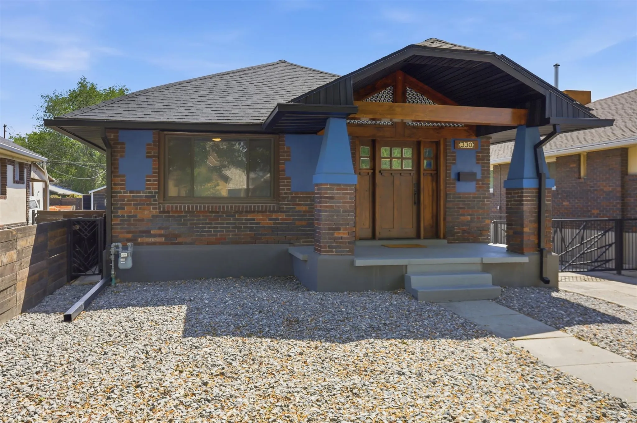 View of front facade with brick siding, a shingled roof, and a porch