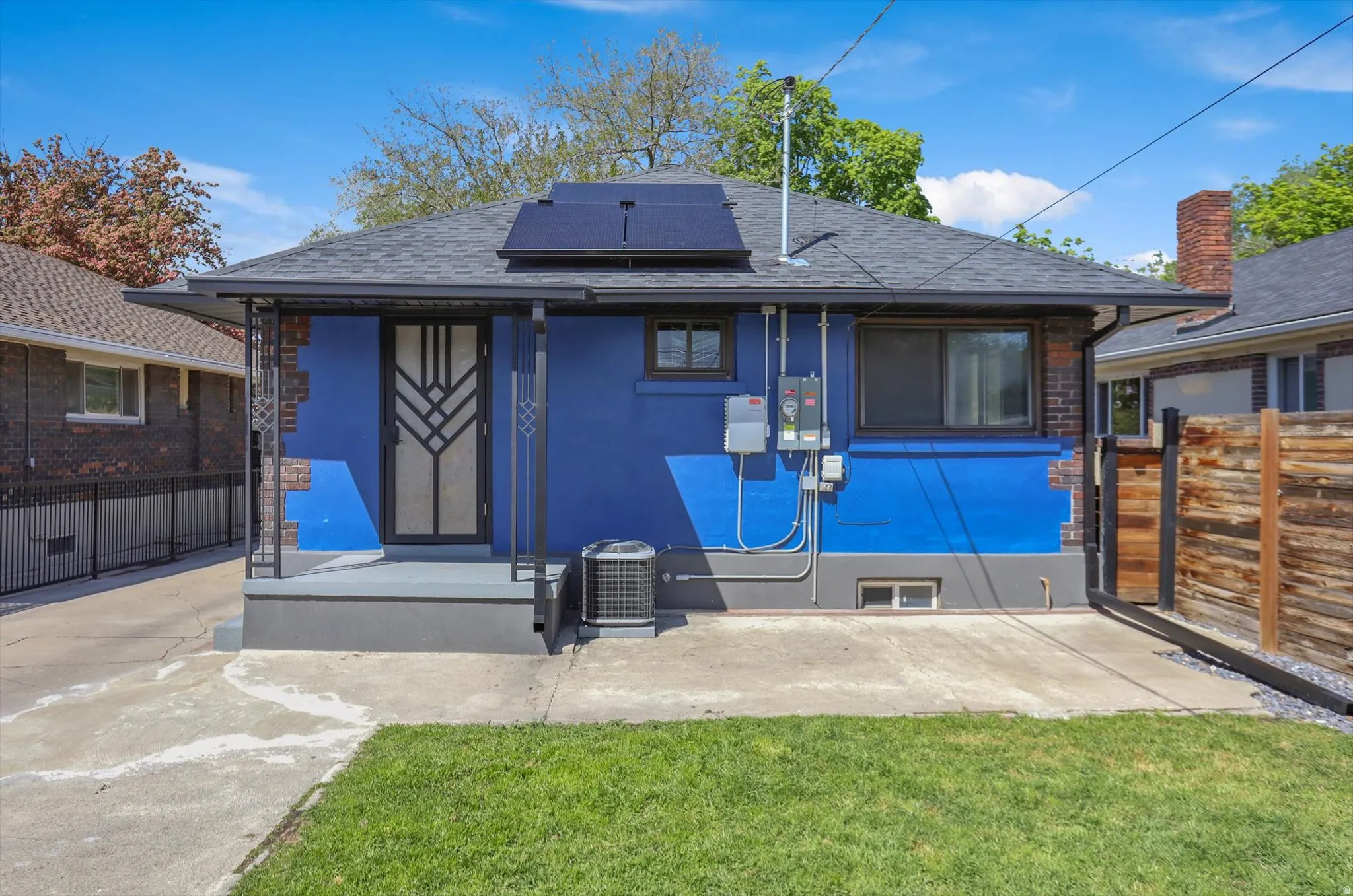 Rear view of property featuring roof mounted solar panels, roof with shingles, and stucco siding