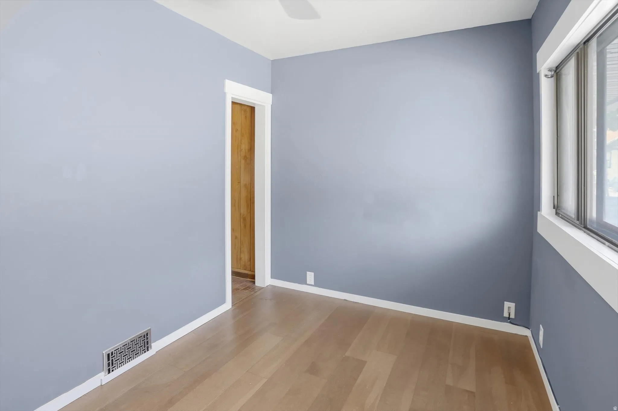 Empty room with light wood-style floors and ceiling fan