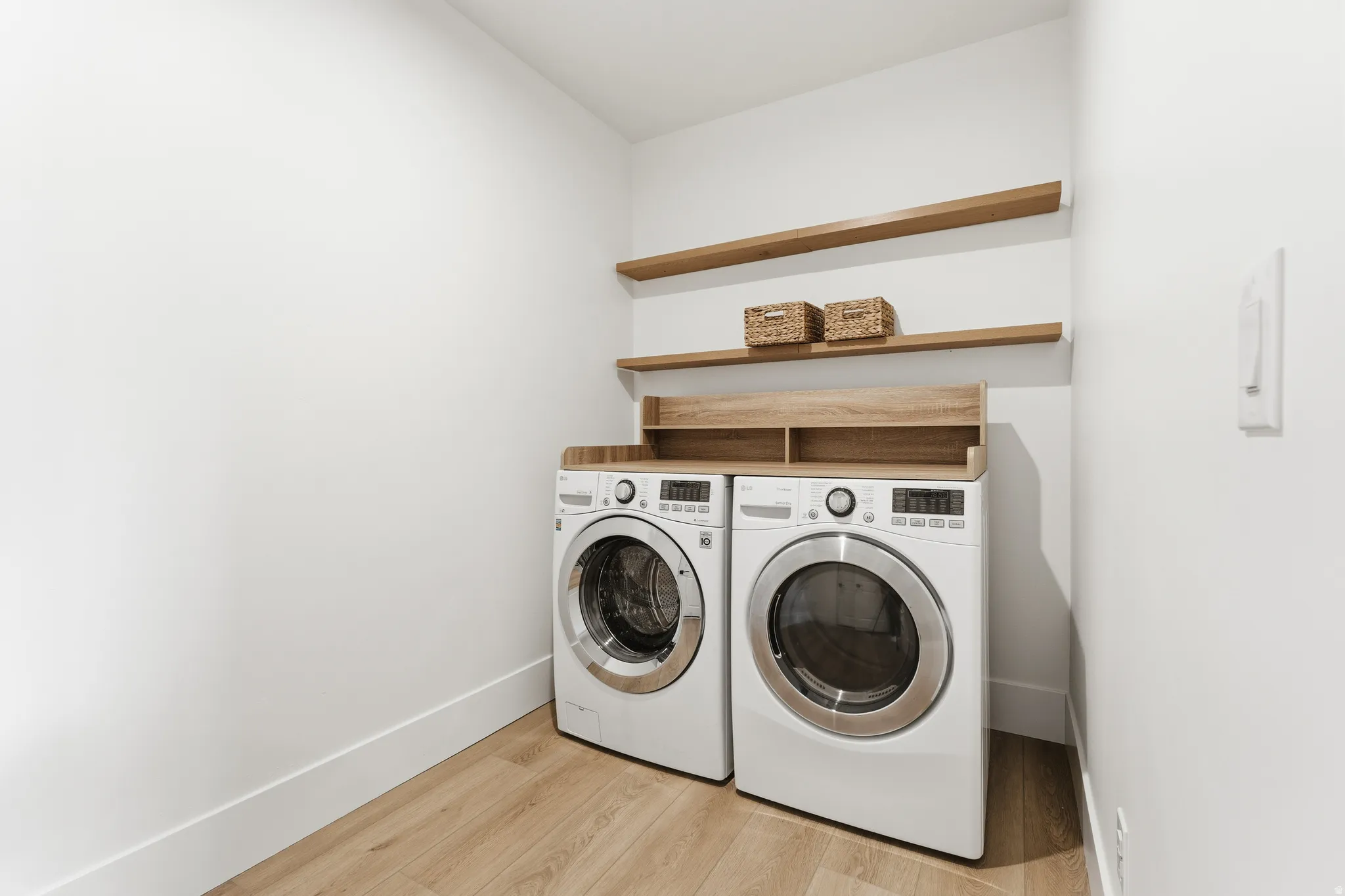 Laundry room with washer and clothes dryer and light wood-type flooring