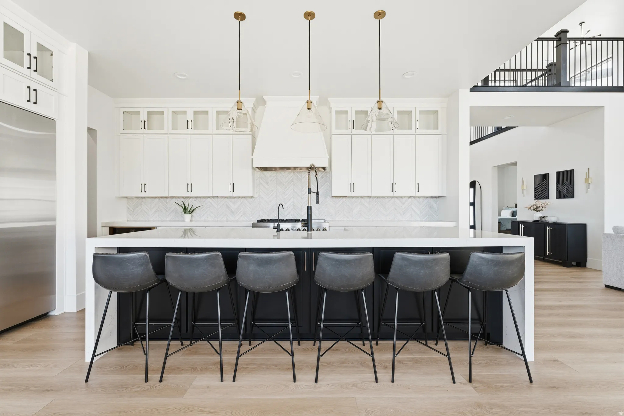 Kitchen with glass insert cabinets, light stone counters, built in refrigerator, a kitchen breakfast bar, and two tone color scheme