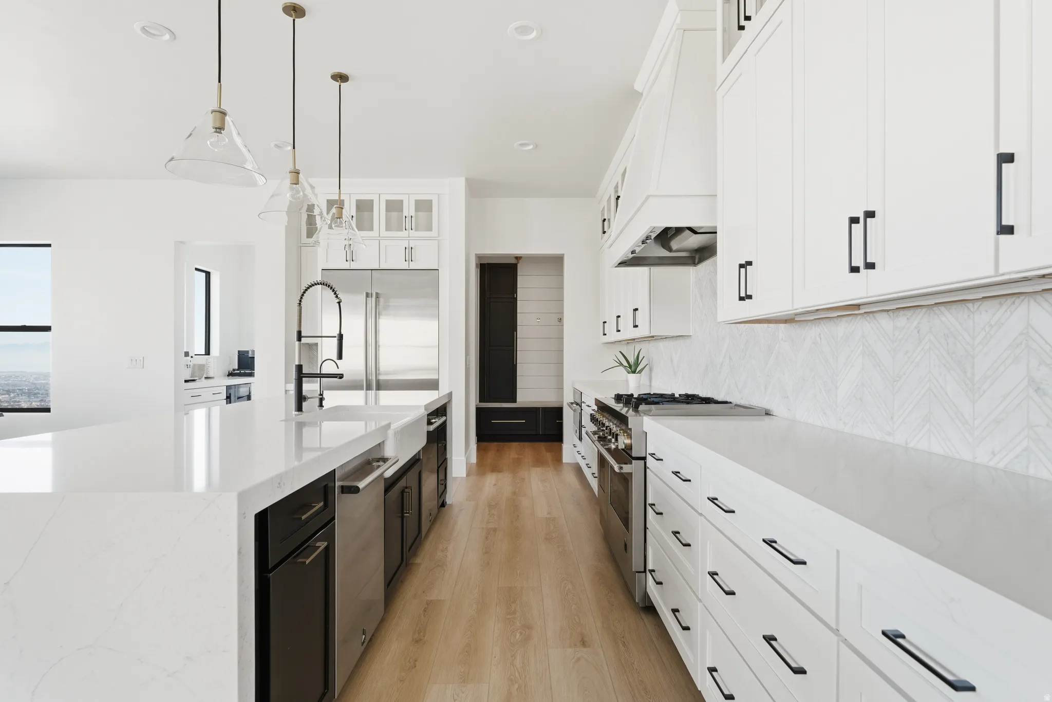 Kitchen with glass fronted cabinets, light stone counters, pendant lighting, light wood finished floors, and high end appliances
