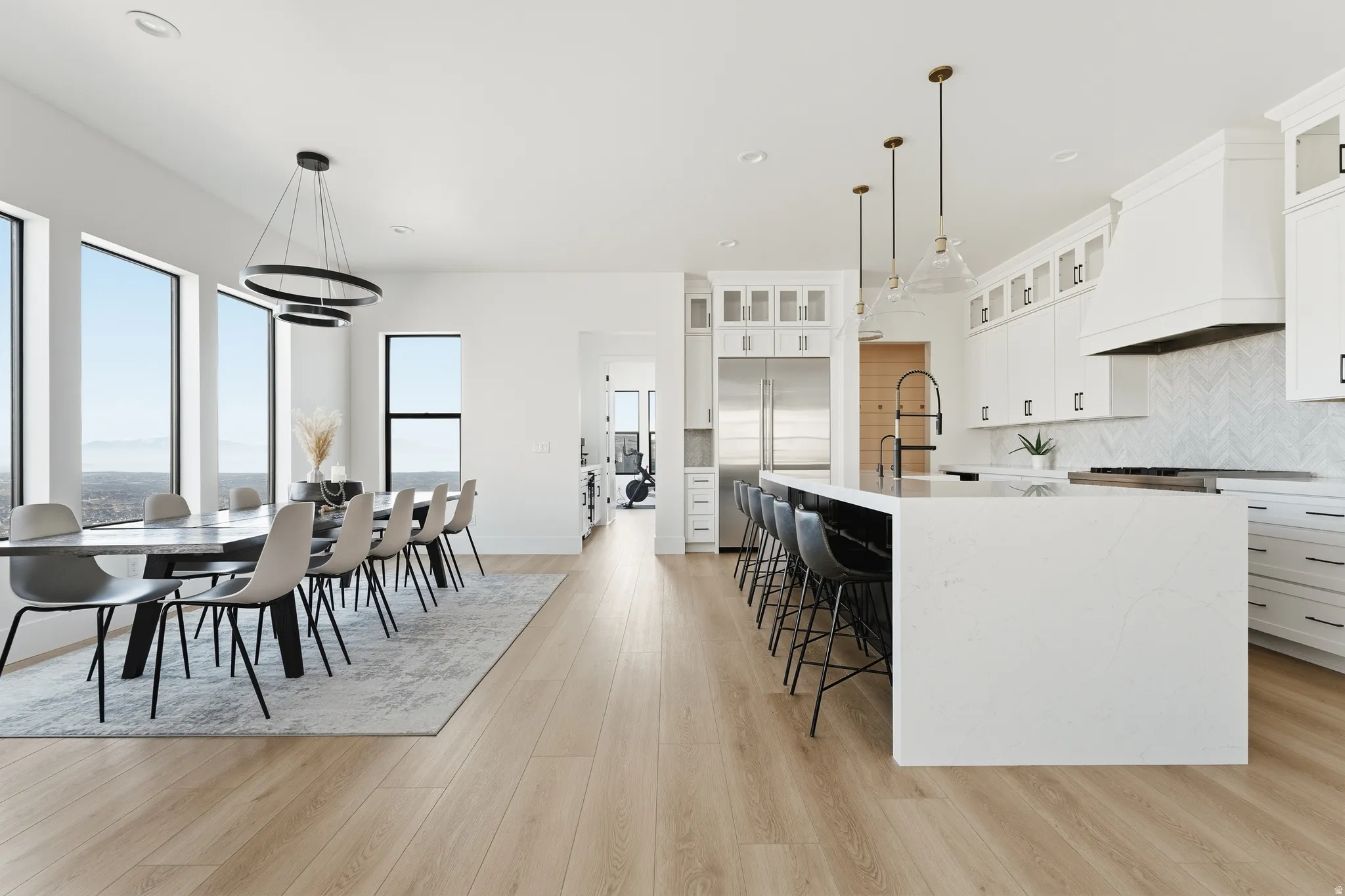 Kitchen featuring white cabinets, stainless steel built in refrigerator, pendant lighting, and light stone counters