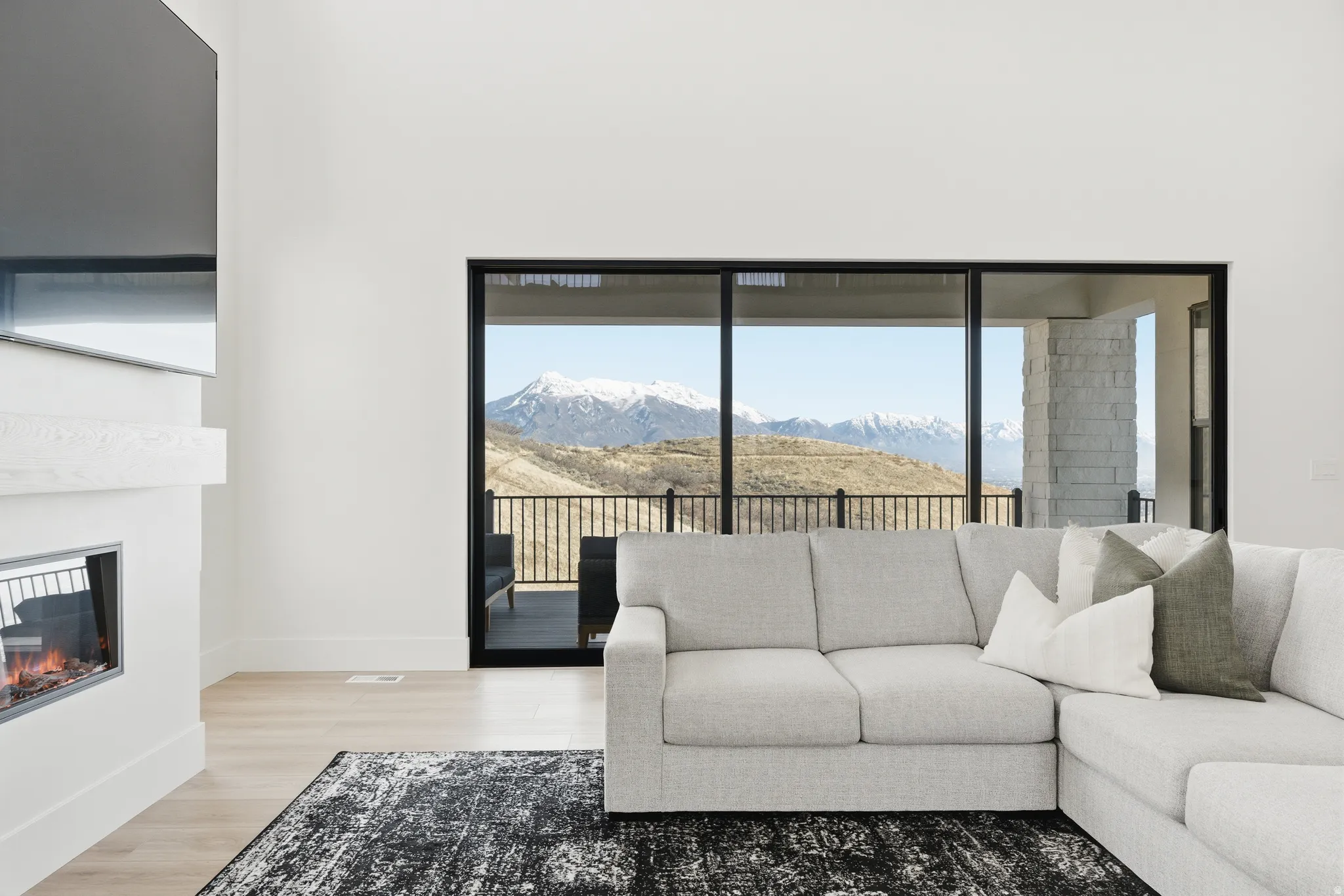 Living area featuring a mountain view, light wood-style flooring, and a glass covered fireplace