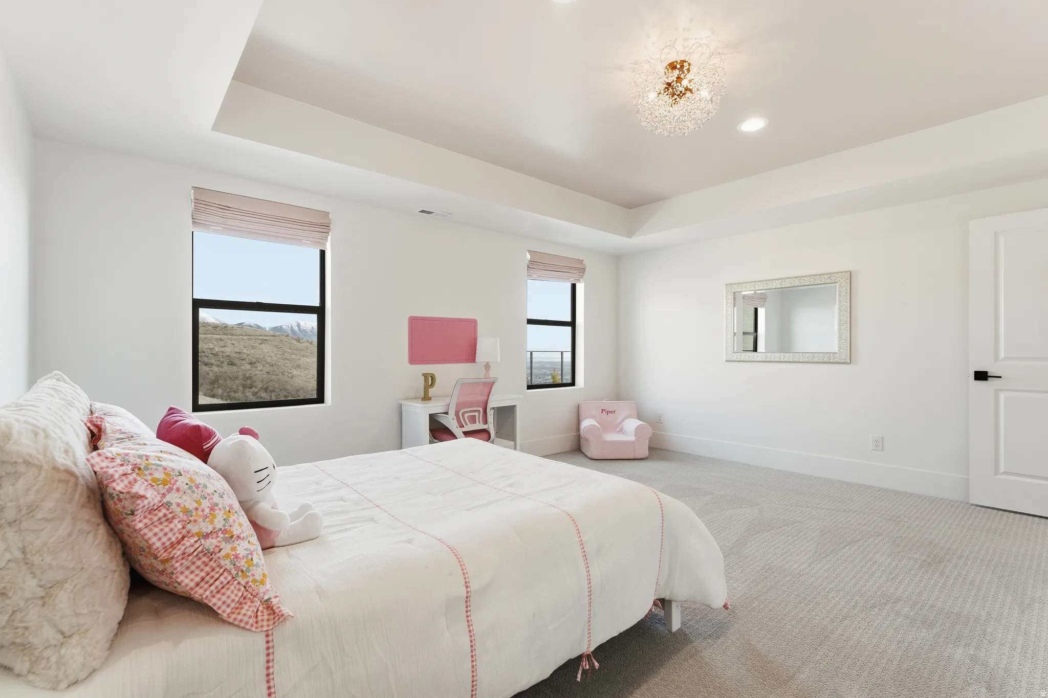 Carpeted bedroom with a raised ceiling and a chandelier