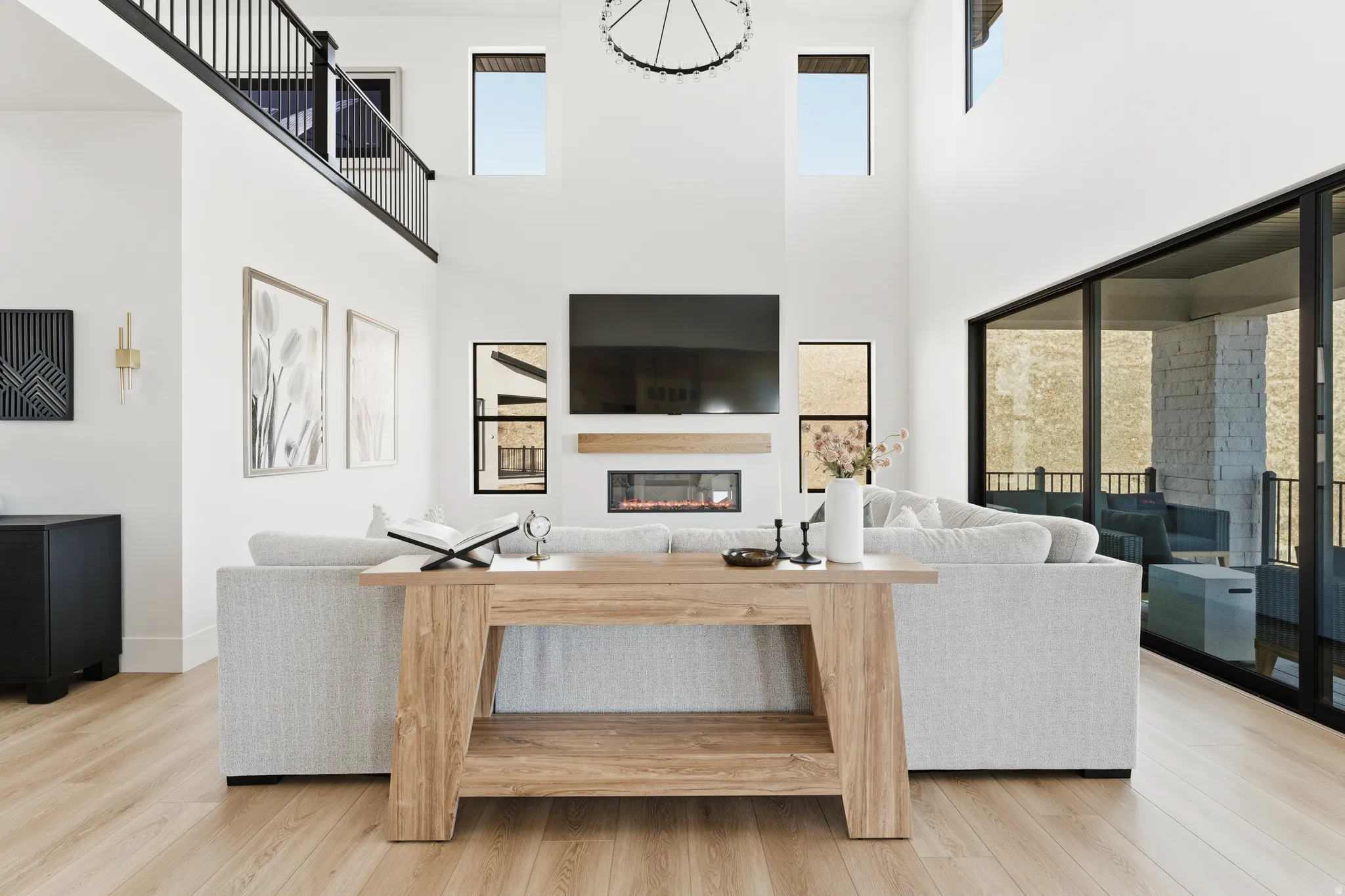 Living room featuring a glass covered fireplace, light wood finished floors, healthy amount of natural light, and a high ceiling