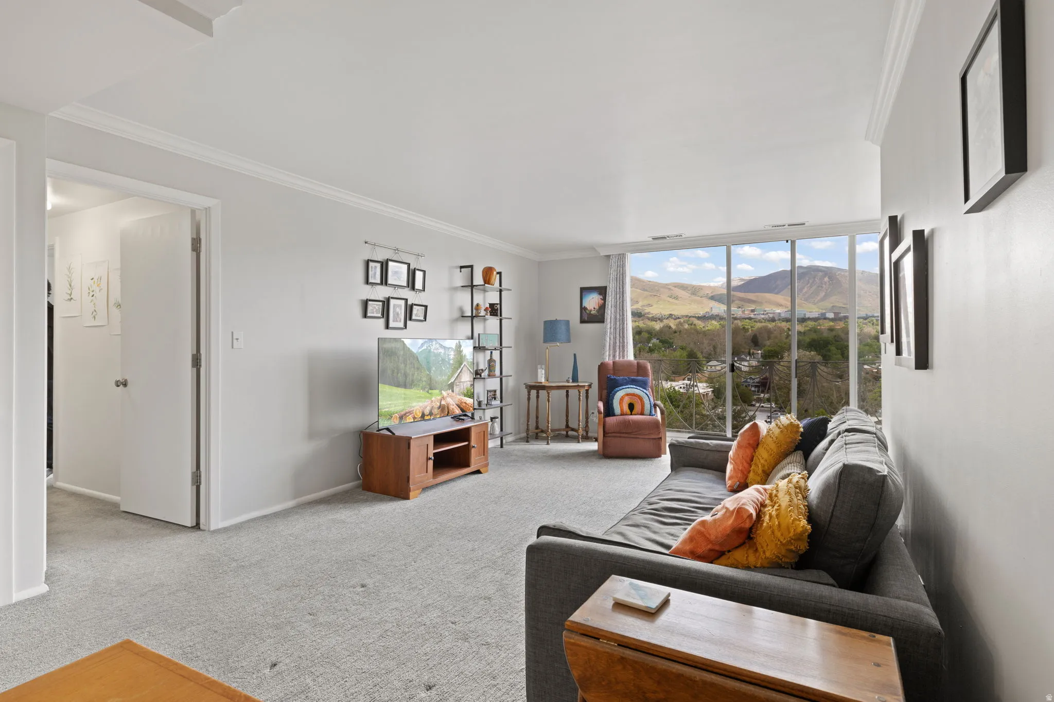 Carpeted living area with crown molding and baseboards