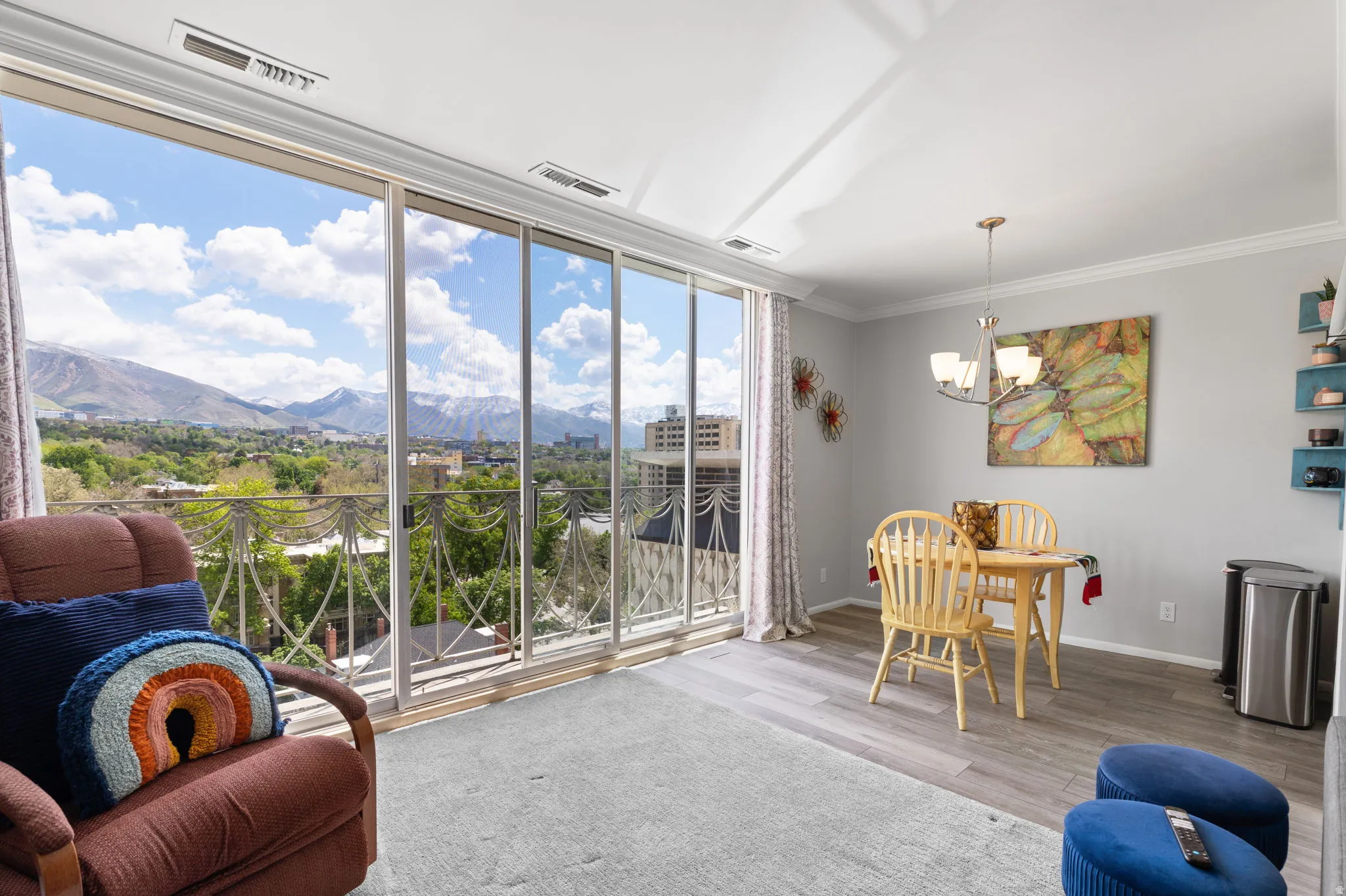 Dining space featuring suspended lighting, a mountain view, light wood-style flooring, crown molding, and floor to ceiling windows