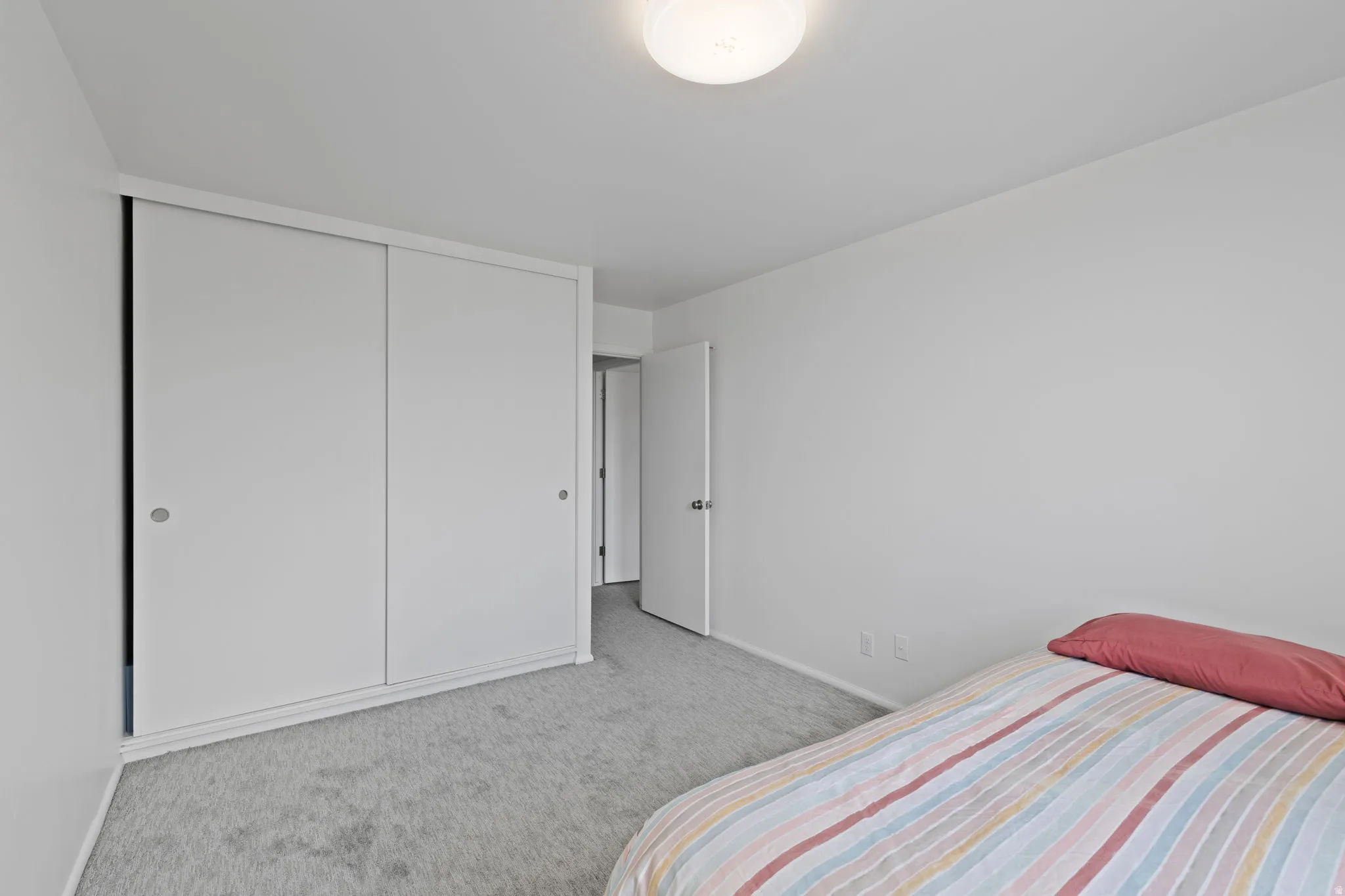Bedroom with light carpet and a closet