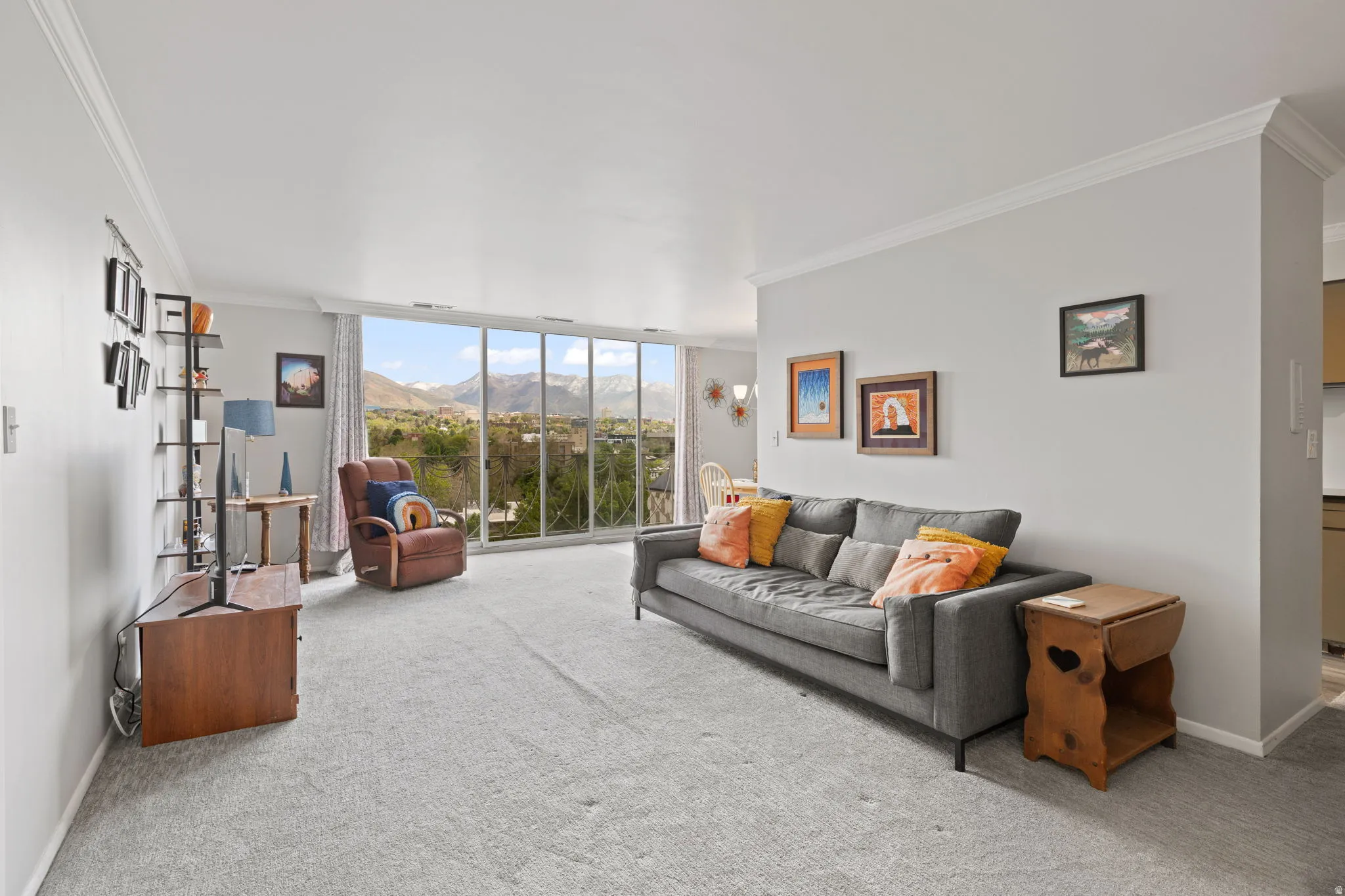 Living area featuring a mountain view, light carpet, ornamental molding, and expansive windows