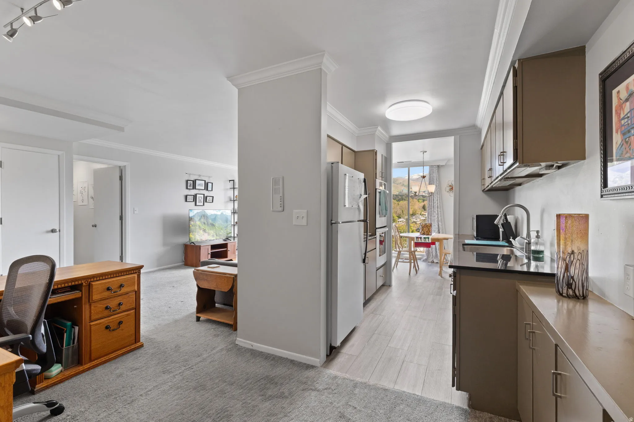 Kitchen featuring freestanding refrigerator, crown molding, and light carpet