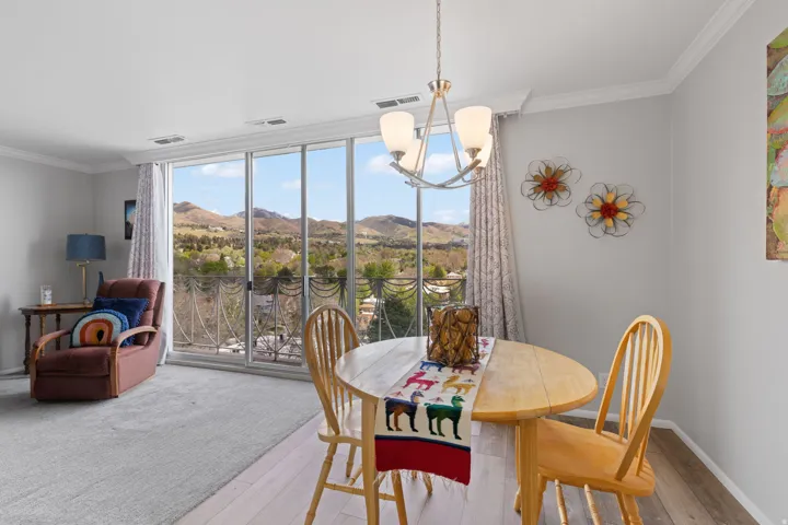 Dining room featuring a mountain view, crown molding, wood-type flooring, and suspended lighting