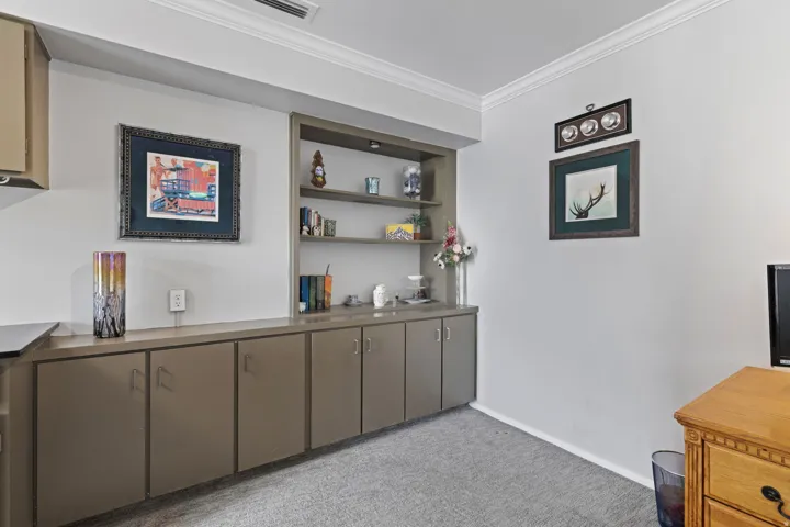 Bar with crown molding, light carpet, and open shelves